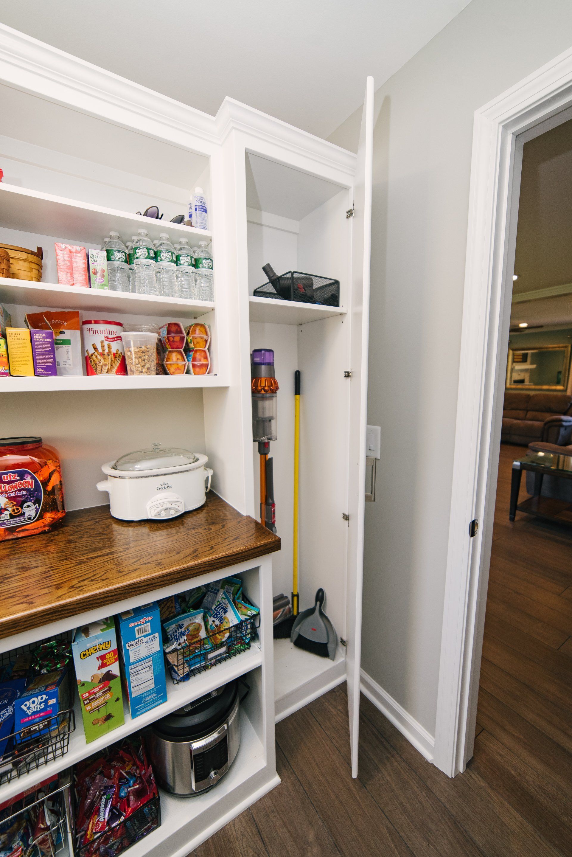 A pantry with a vacuum cleaner and a broom in it.