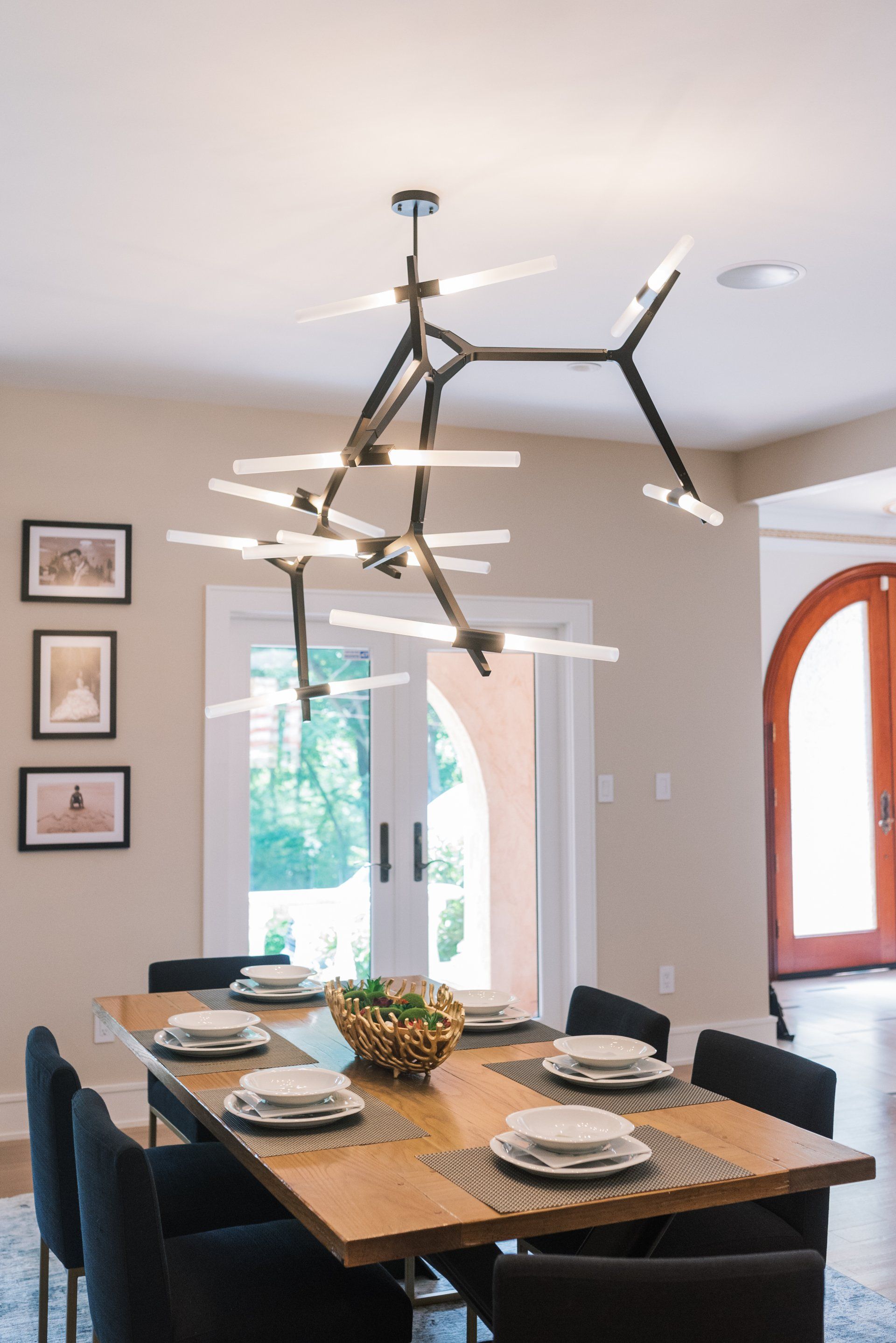 A dining room with a table and chairs and a chandelier hanging from the ceiling