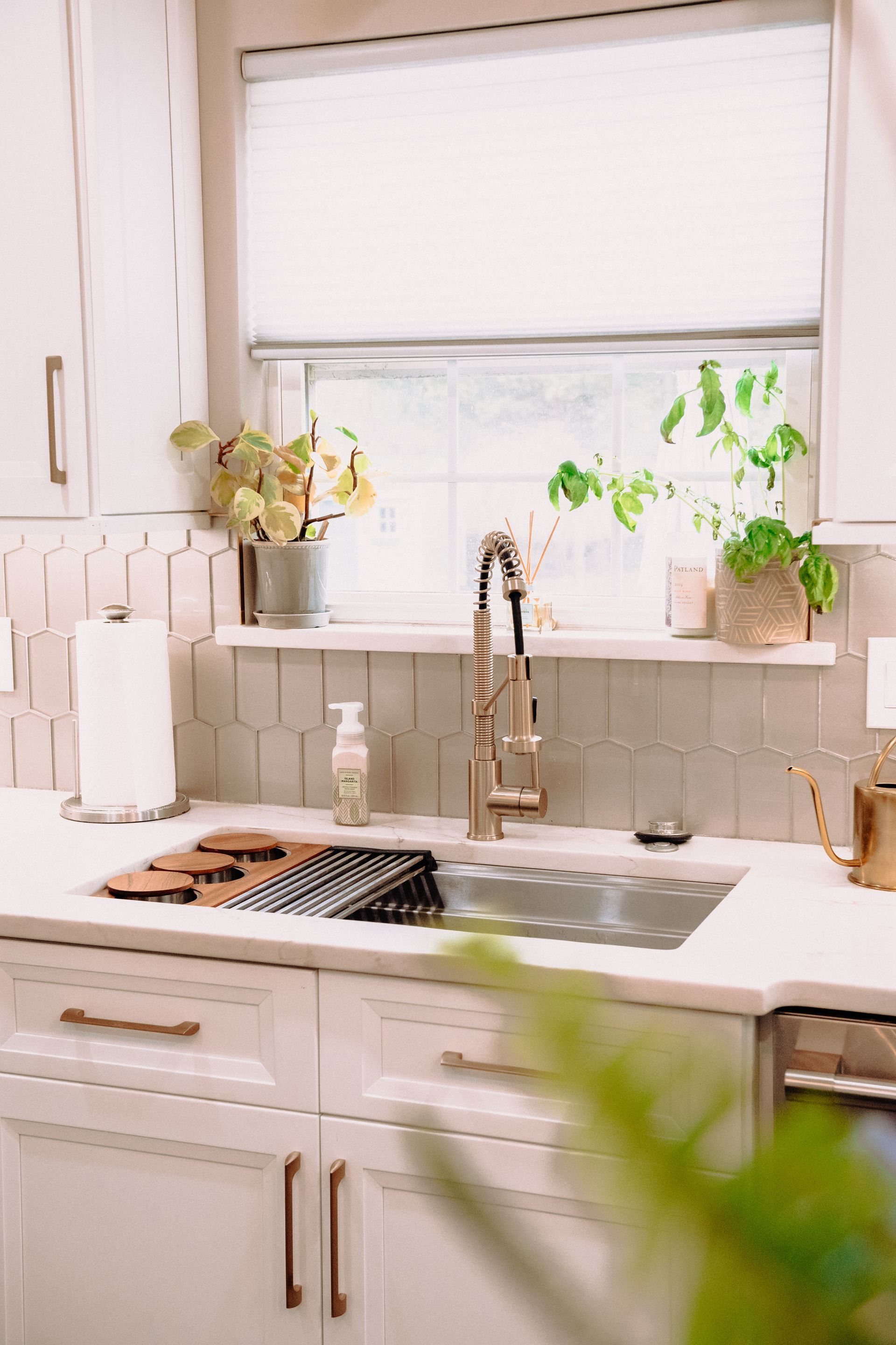 A kitchen with white cabinets , a sink , and a window.