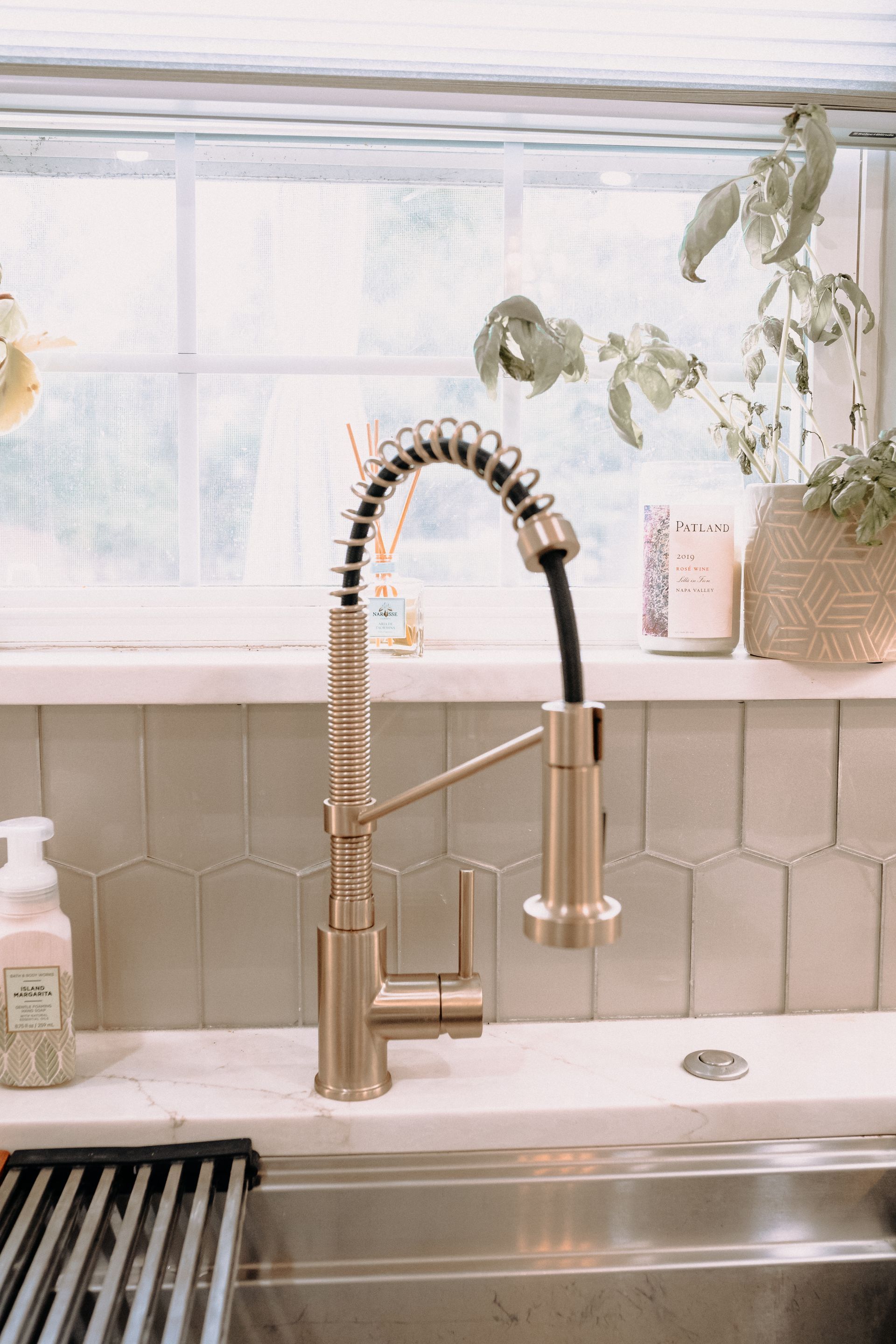 A kitchen sink with a faucet and a window in the background.