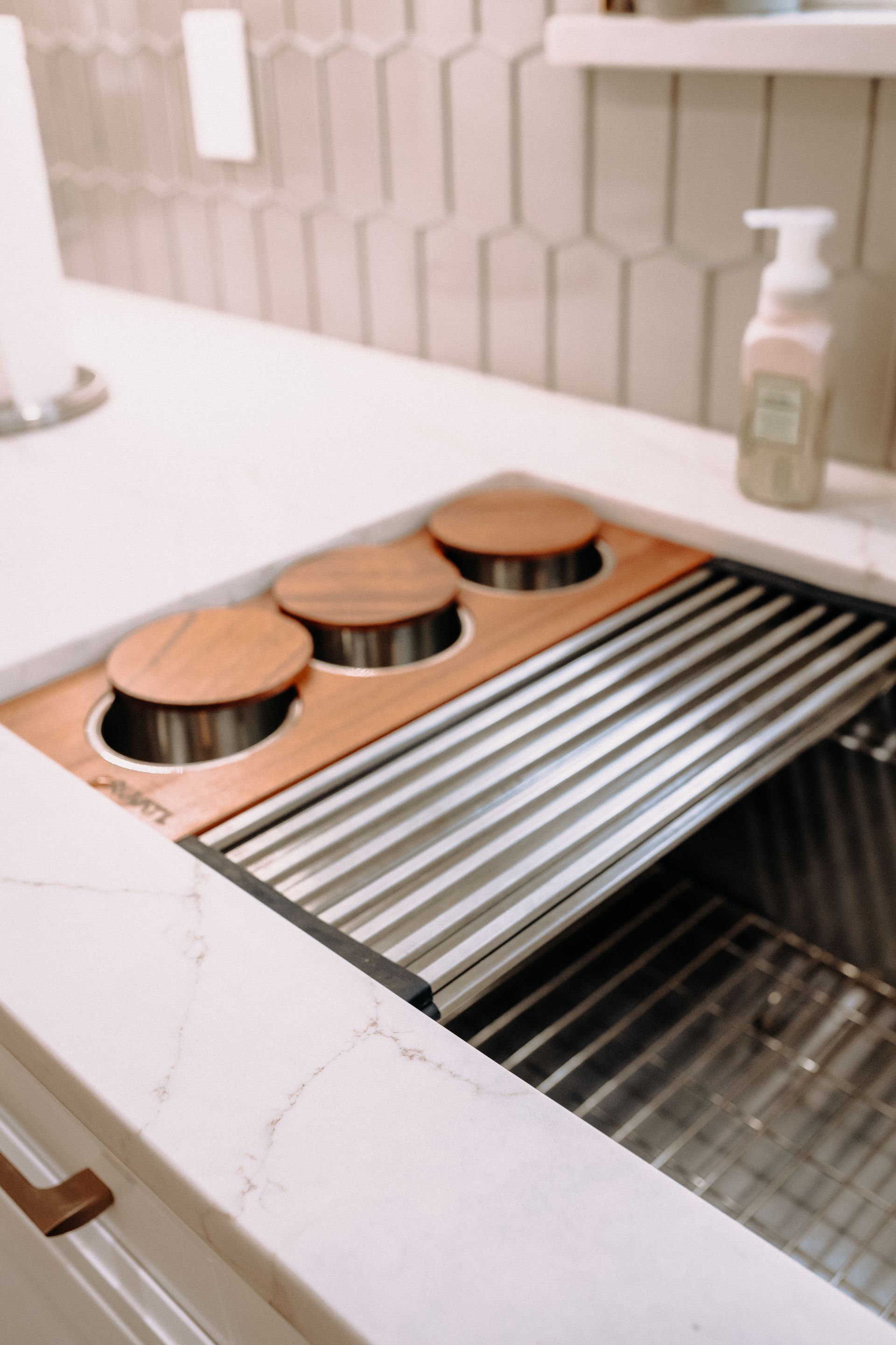 A kitchen sink with wooden lids and a soap dispenser on the counter.