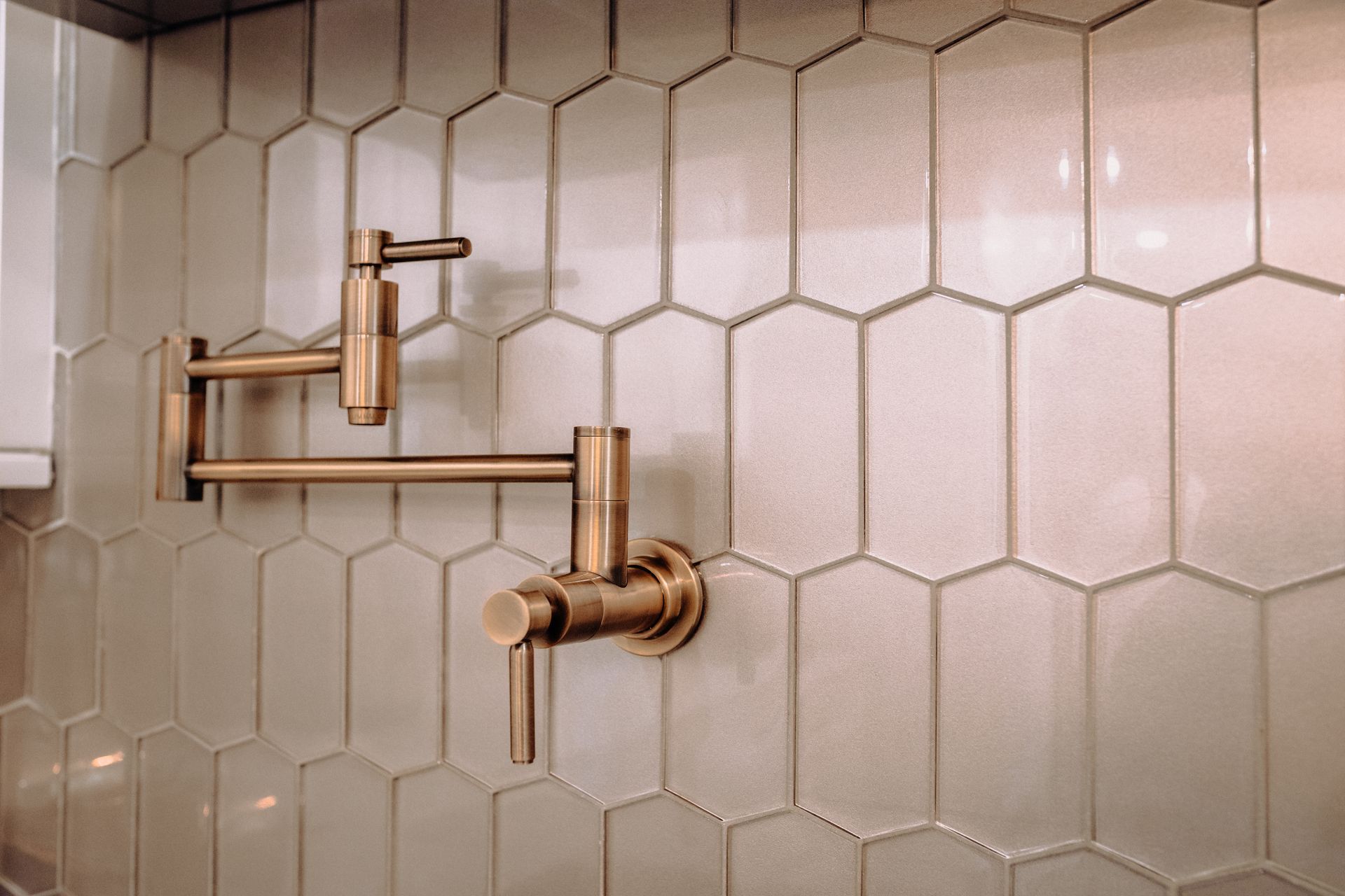 A faucet is hanging on a tiled wall in a kitchen.