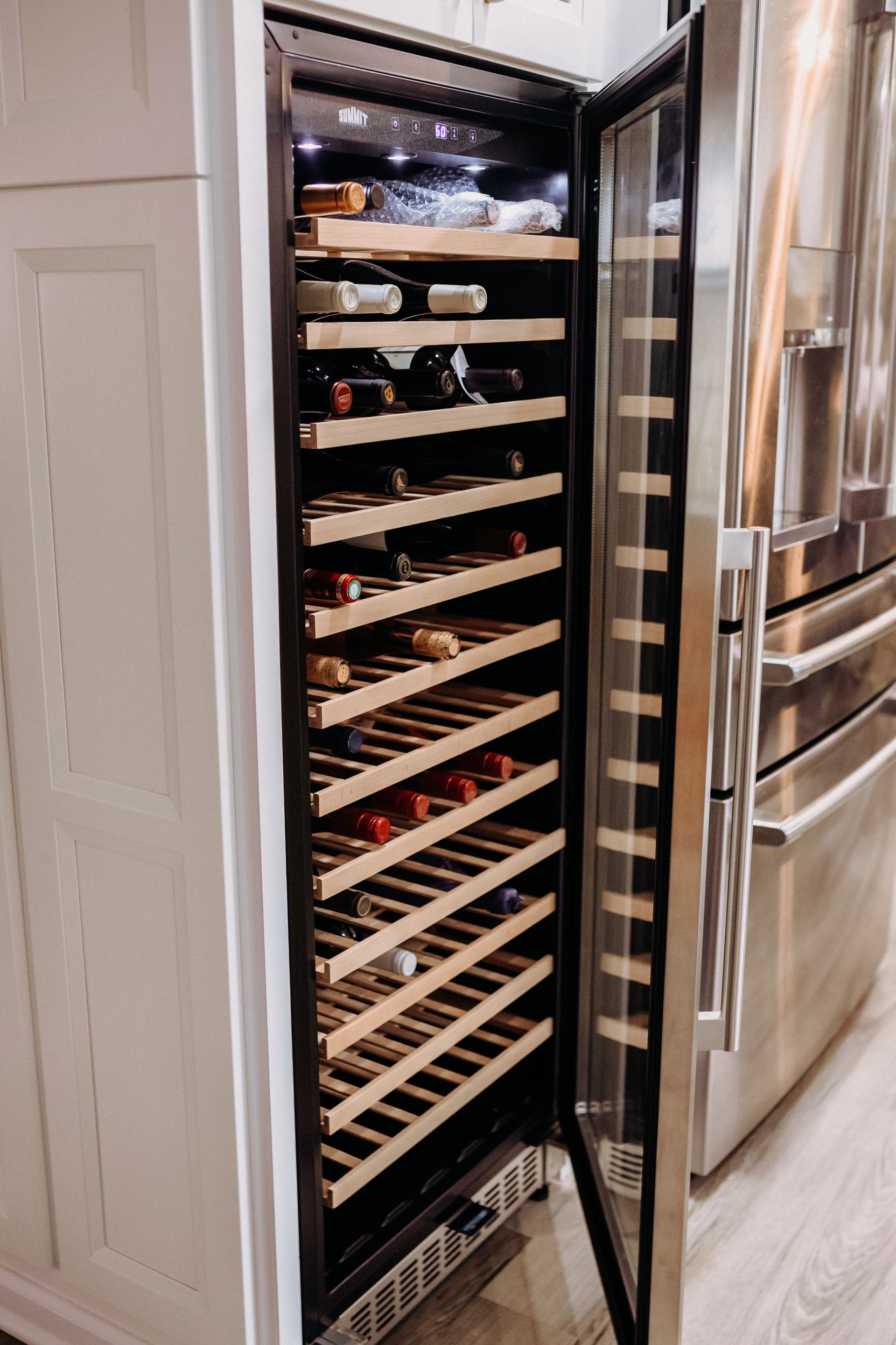 A wine cooler filled with bottles of wine in a kitchen.