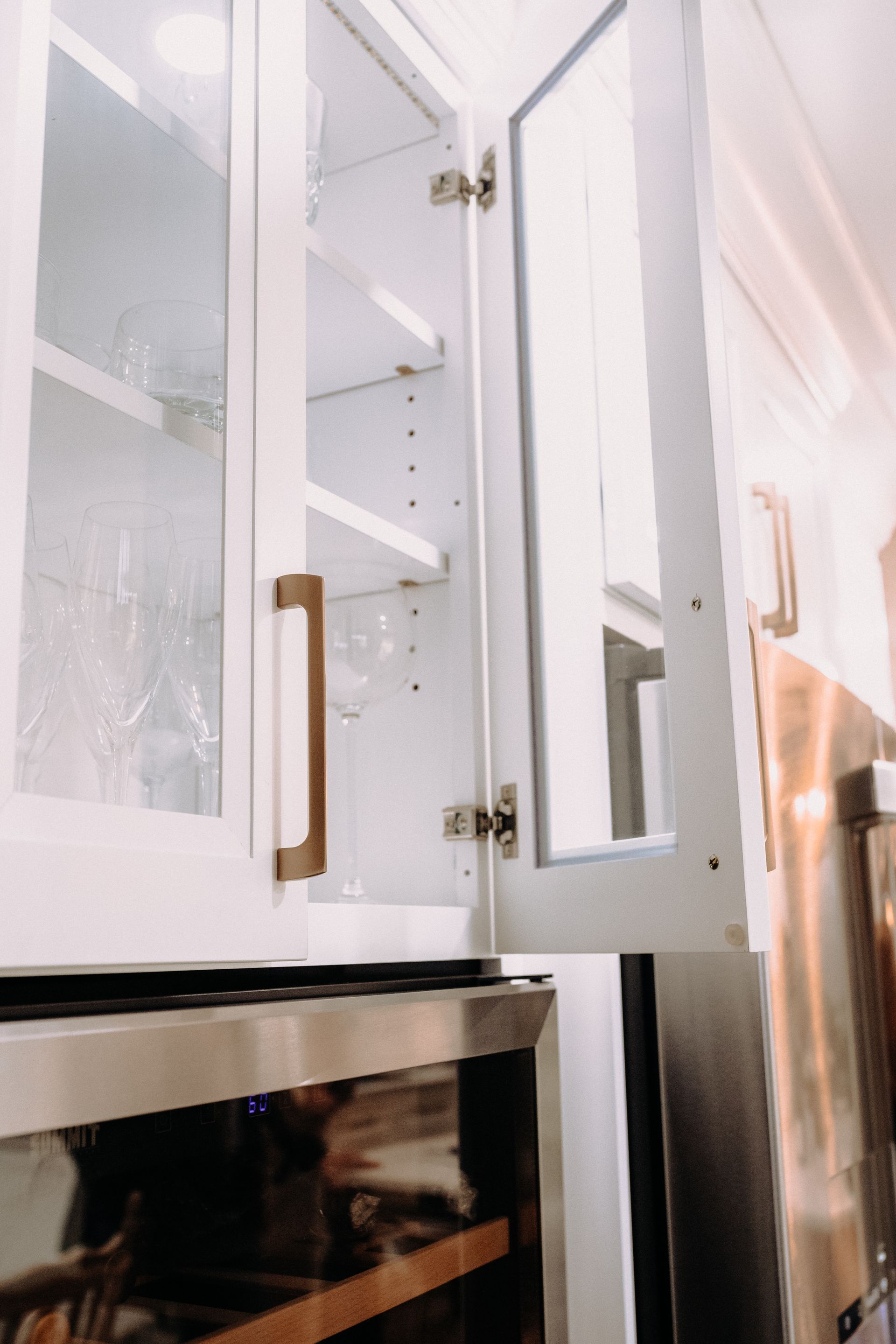 A kitchen with stainless steel appliances and white cabinets with glass doors.