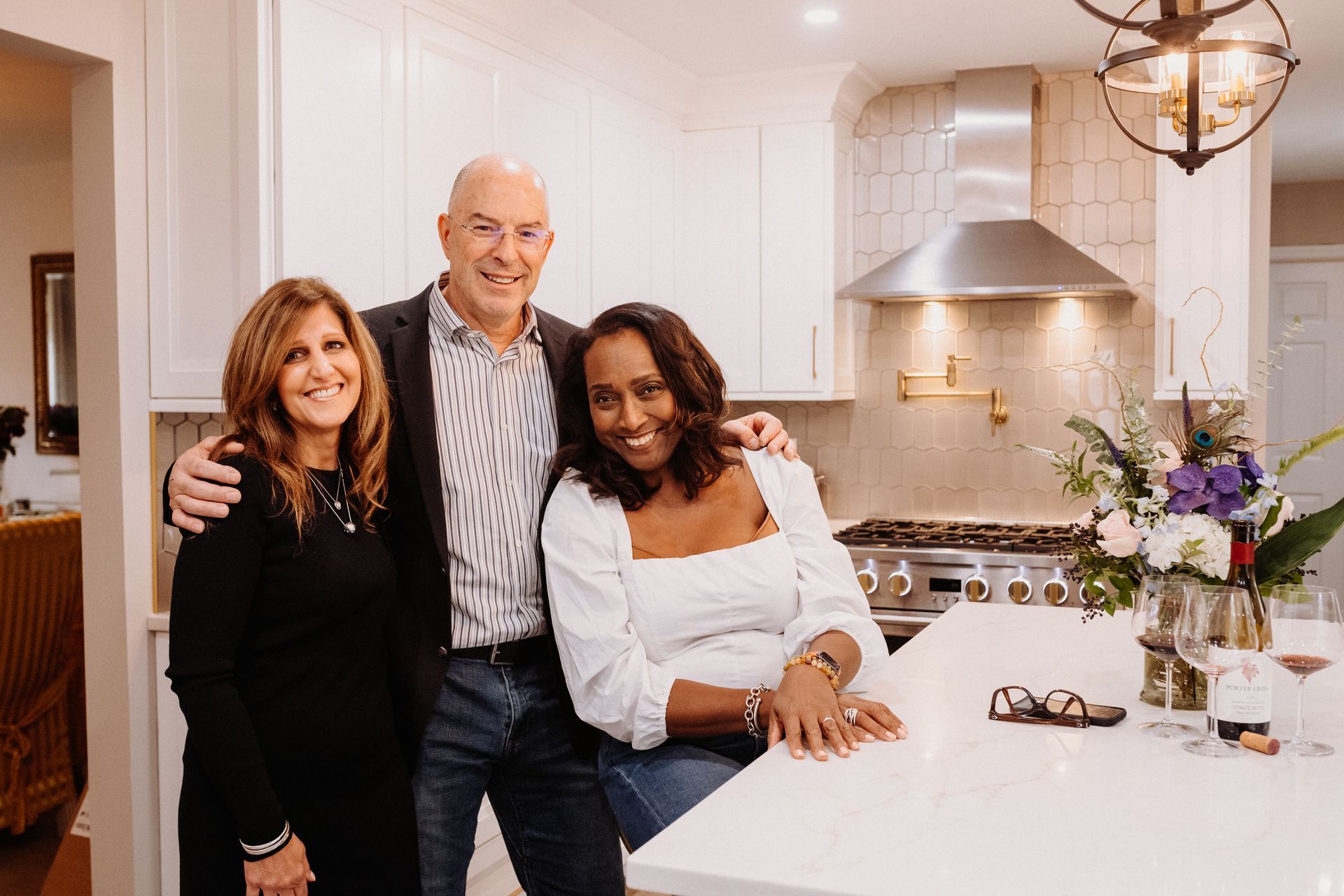 A man and two women are posing for a picture in a kitchen.