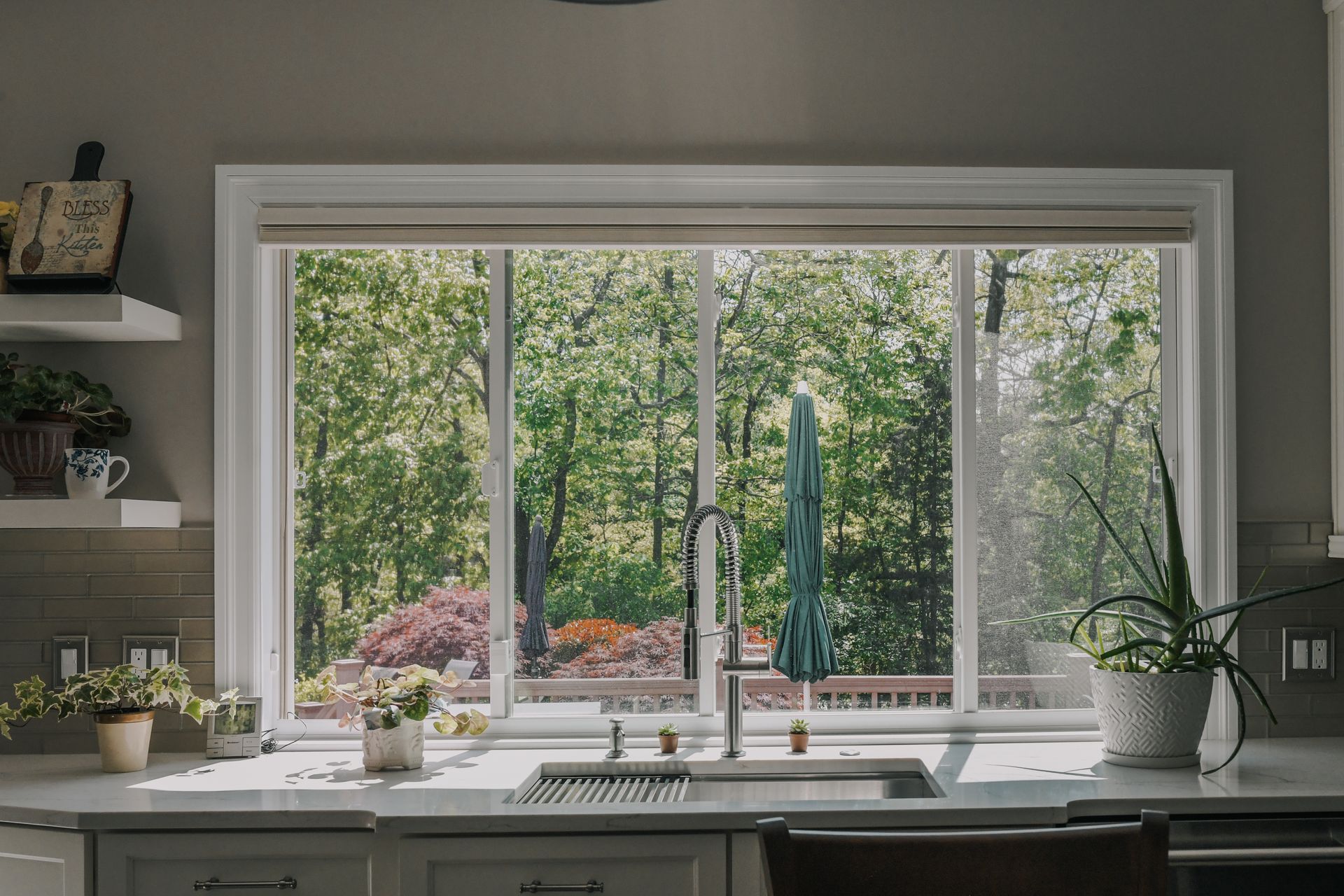 A kitchen with a sink and a large window with a view of the woods.