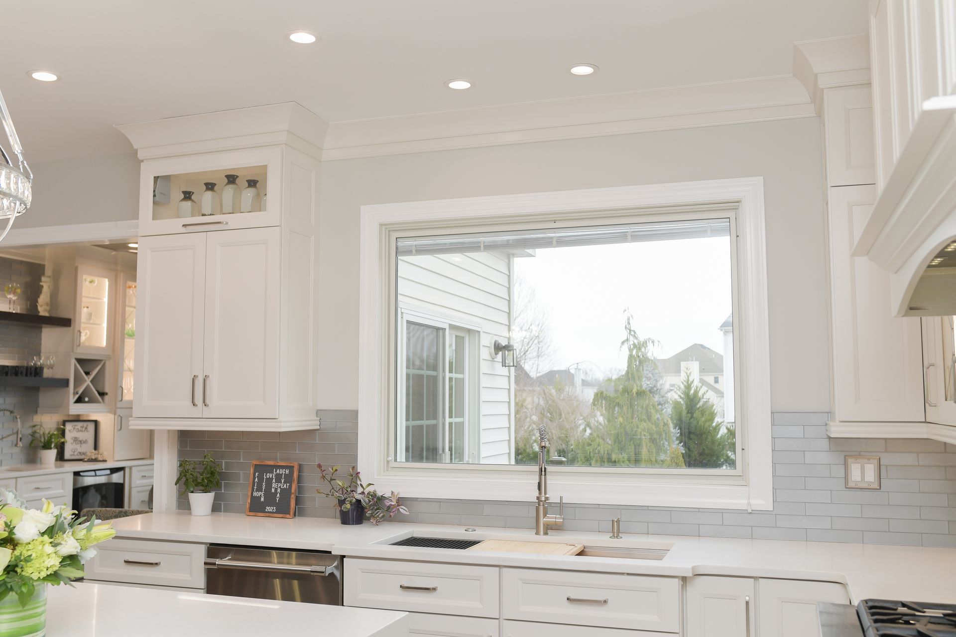 A kitchen with white cabinets and a large window