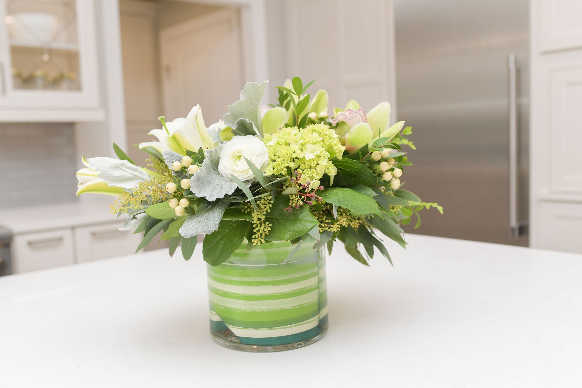 A vase filled with flowers is sitting on a counter in a kitchen.
