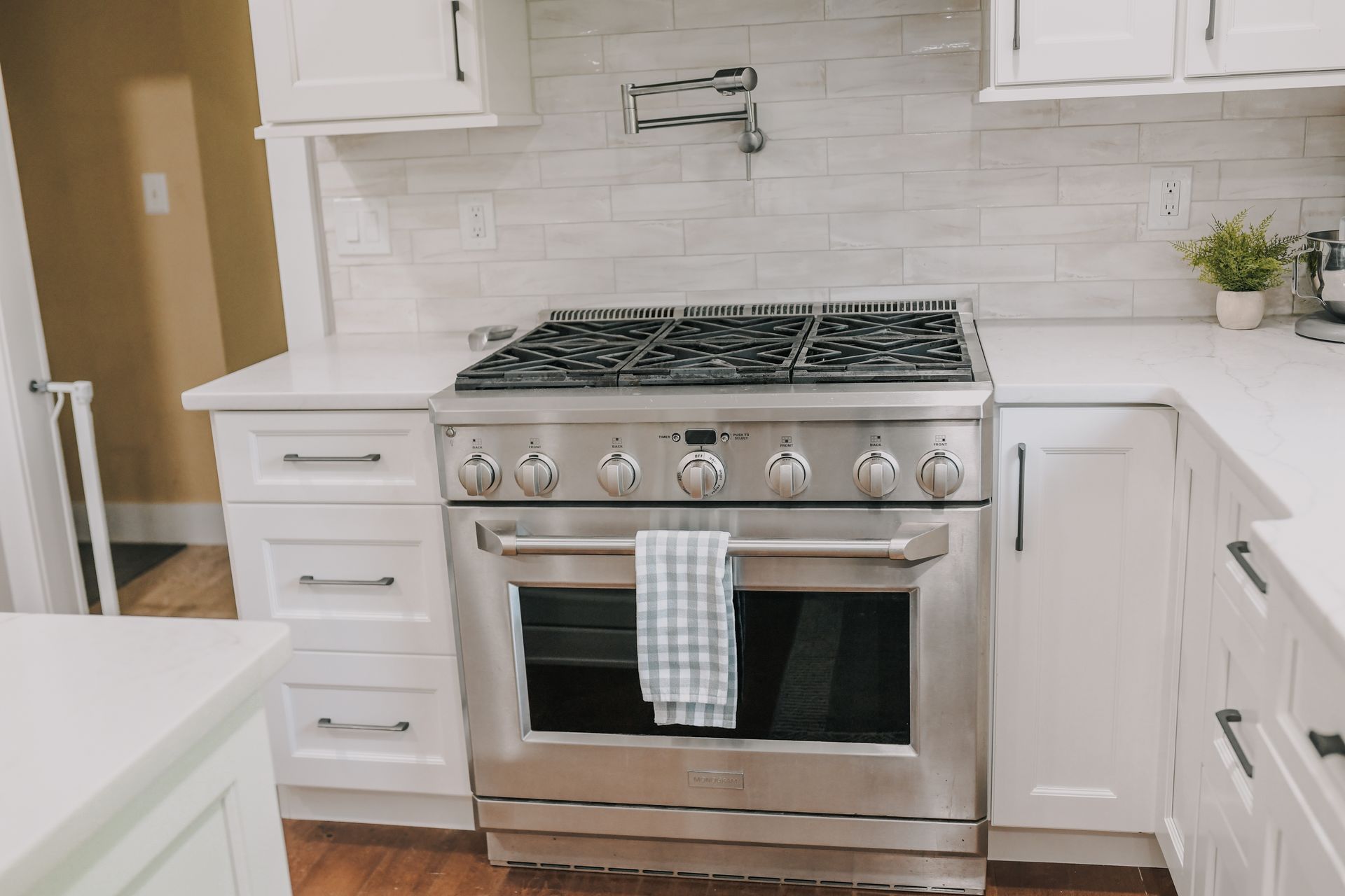 A stainless steel stove and oven in a kitchen with white cabinets.