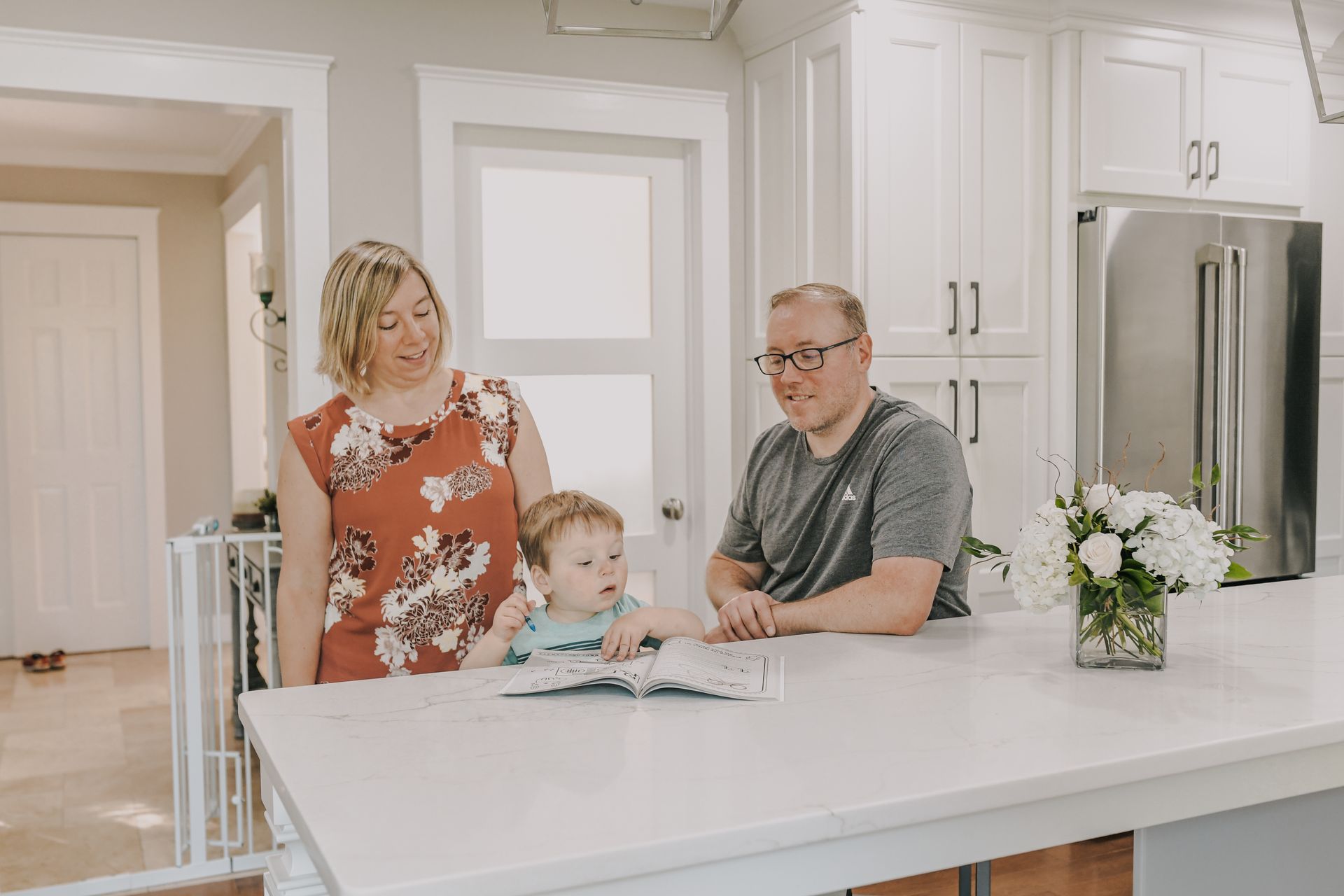 A family is sitting at a table in a kitchen looking at a book.