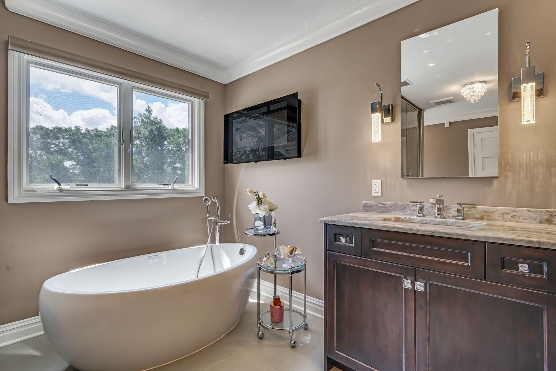 A bathroom with a tub , sink , mirror and television.