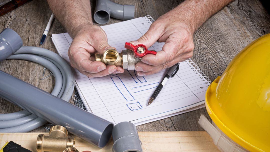A plumber is working on a pipe on a wooden table.