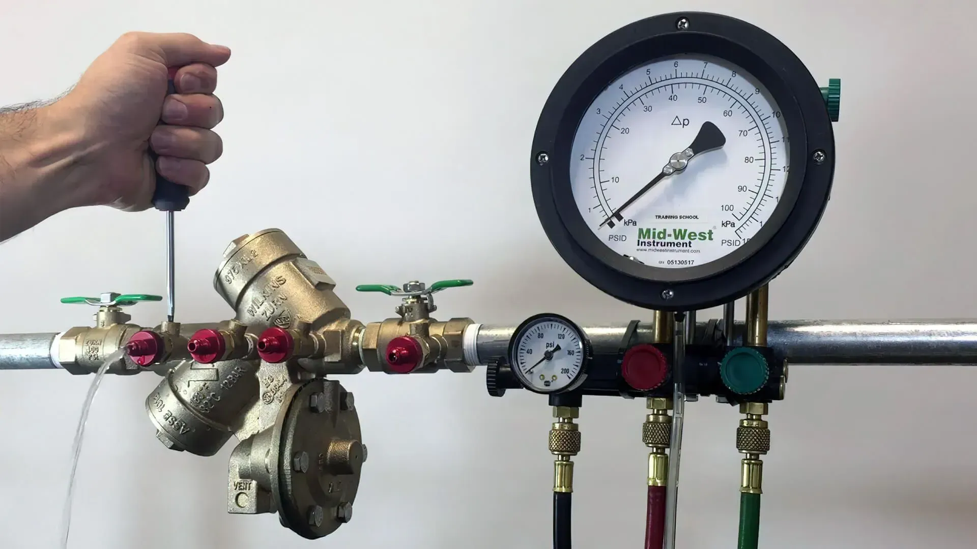 A person is holding a screwdriver next to a pressure gauge