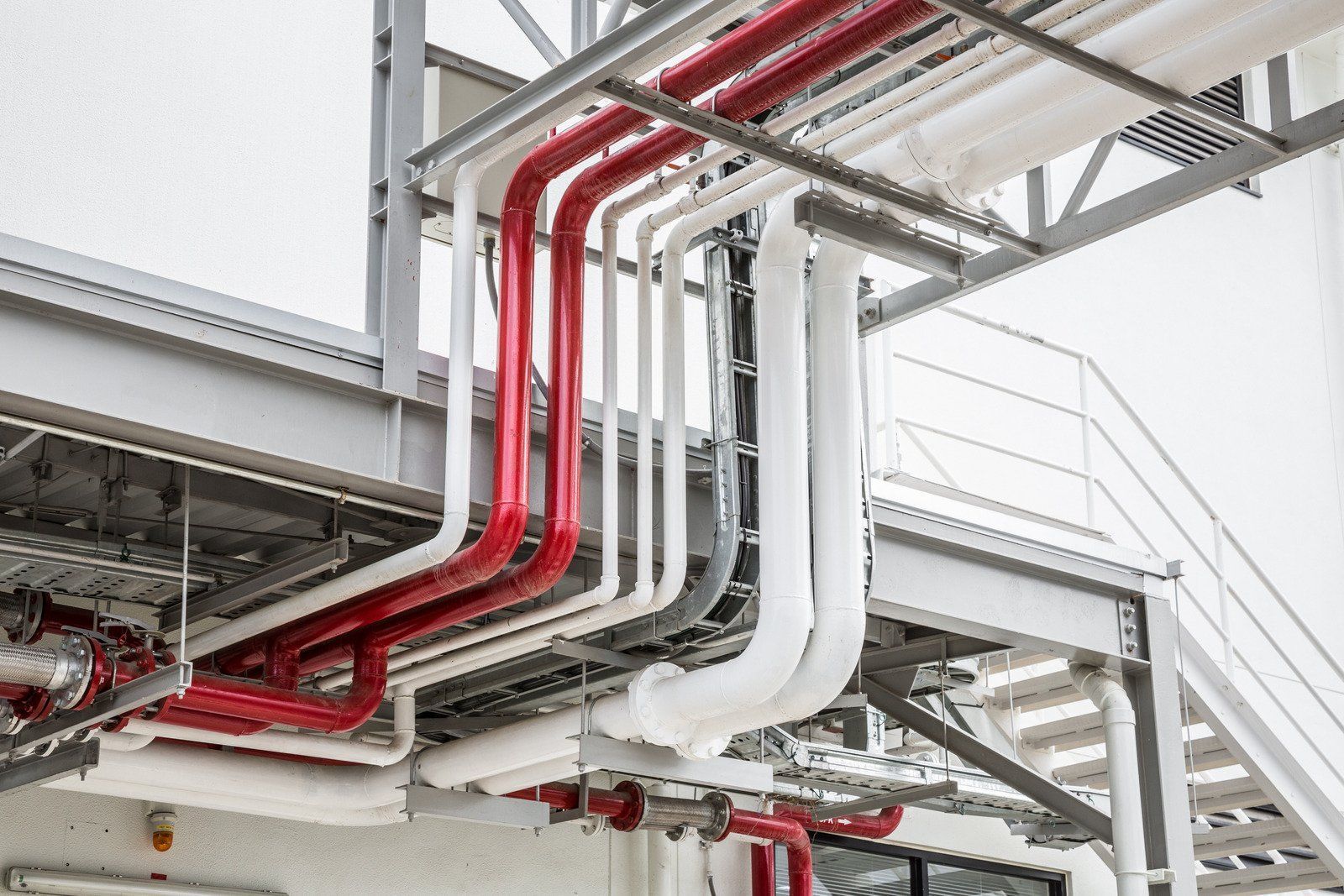 A bunch of pipes are hanging from the ceiling of a building.