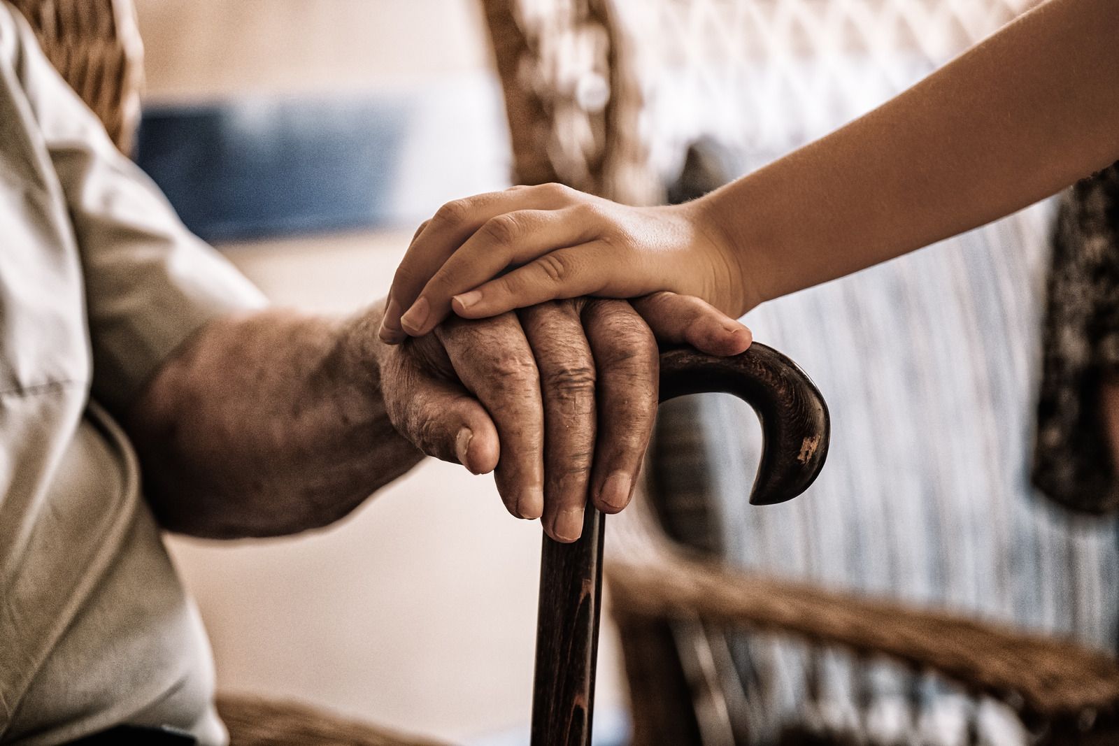 An elderly man is holding a child 's hand while sitting in a chair.
