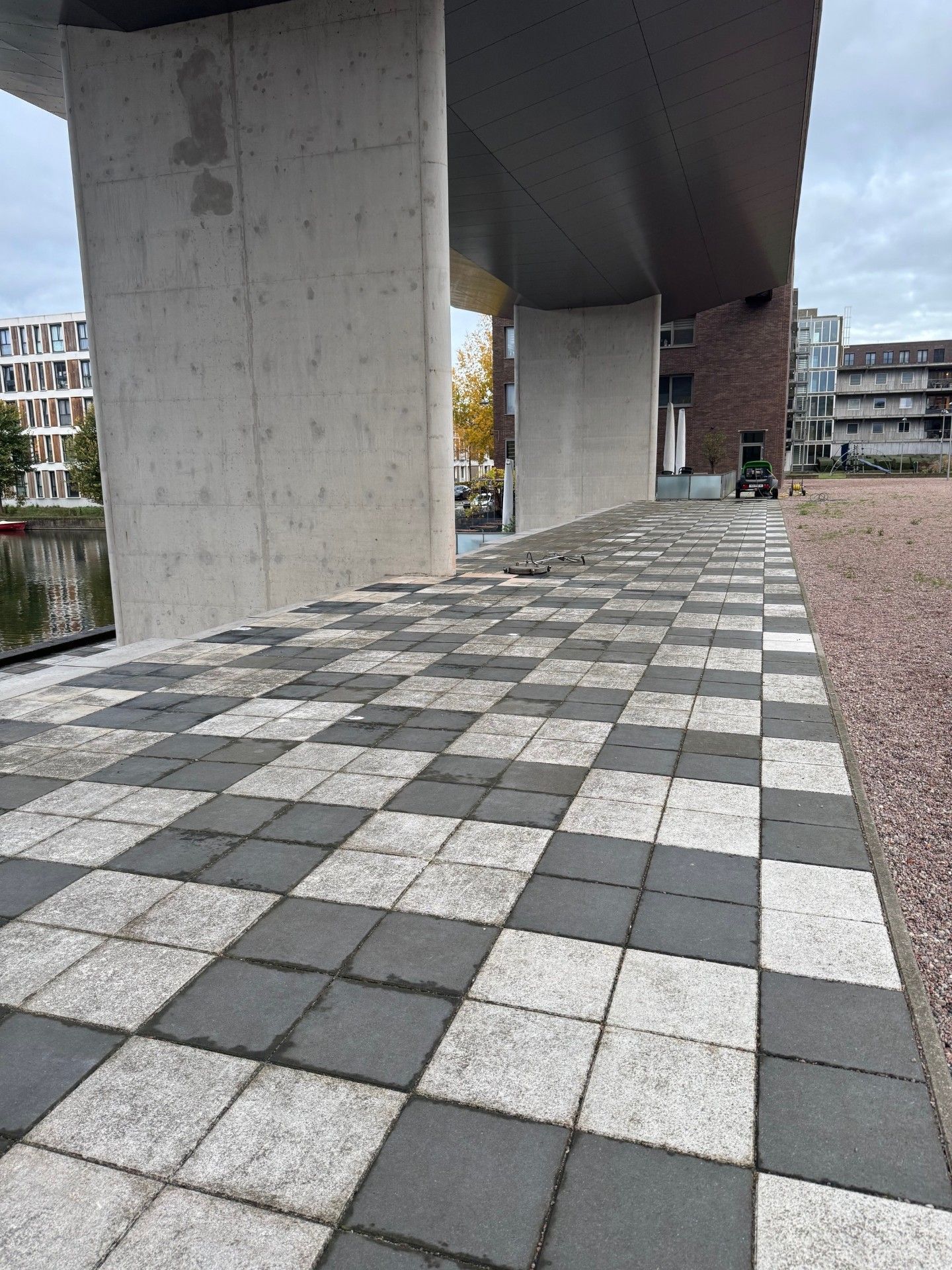 Dambordpad onder een betonnen constructie. Gebouwen op de achtergrond.