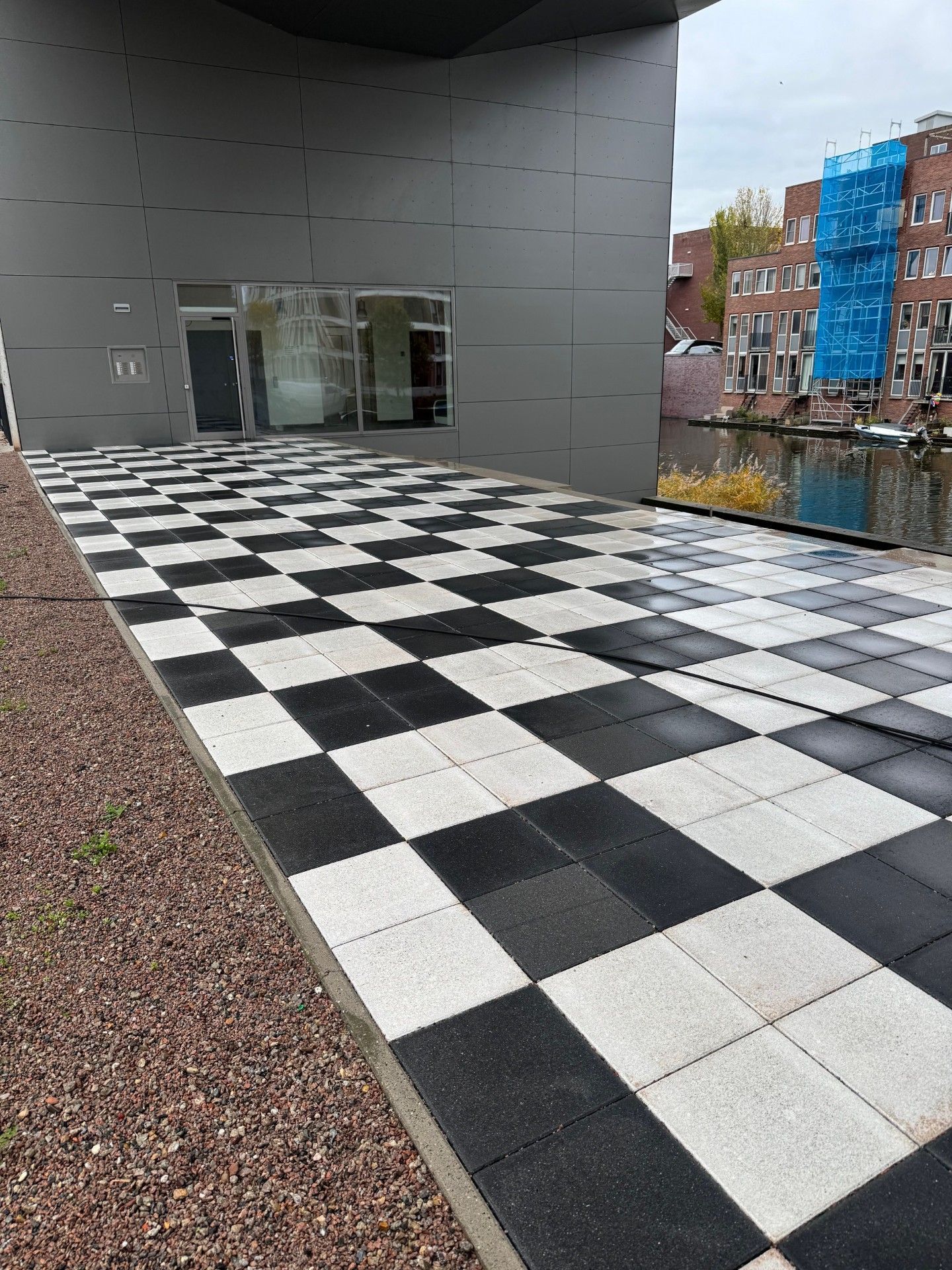 Zwart-wit geblokte tegelpatio buiten een modern gebouw.