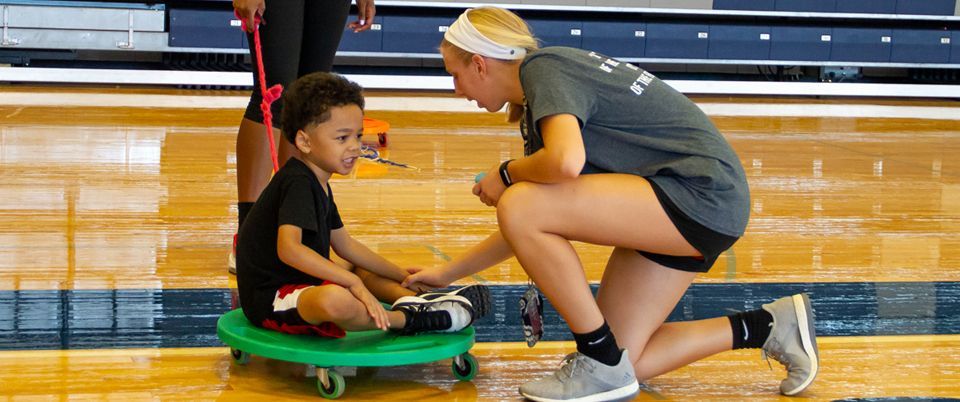 KEEN Athlete on Scooter with Volunteer kneeling and helping