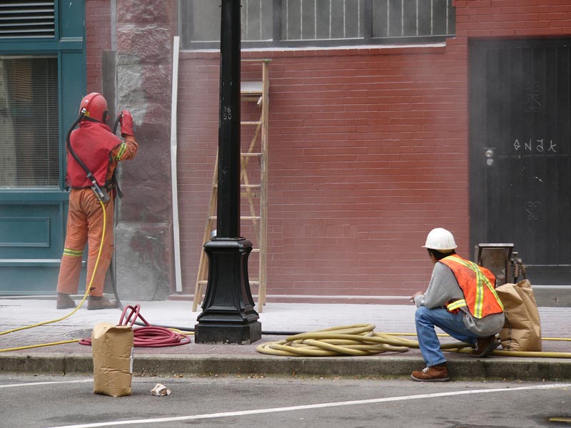 worker sandblasting building paint