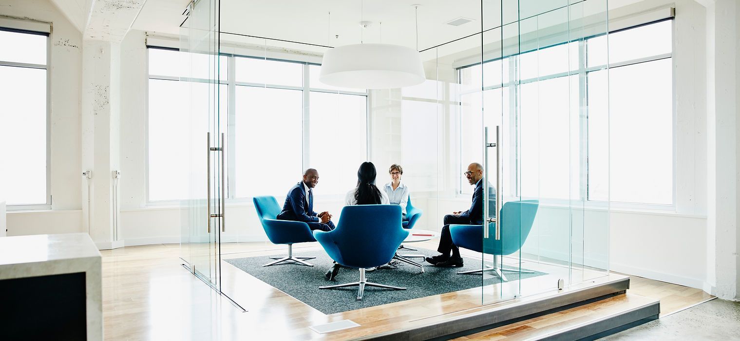 A Group of People Are Sitting in Chairs in a Conference Room