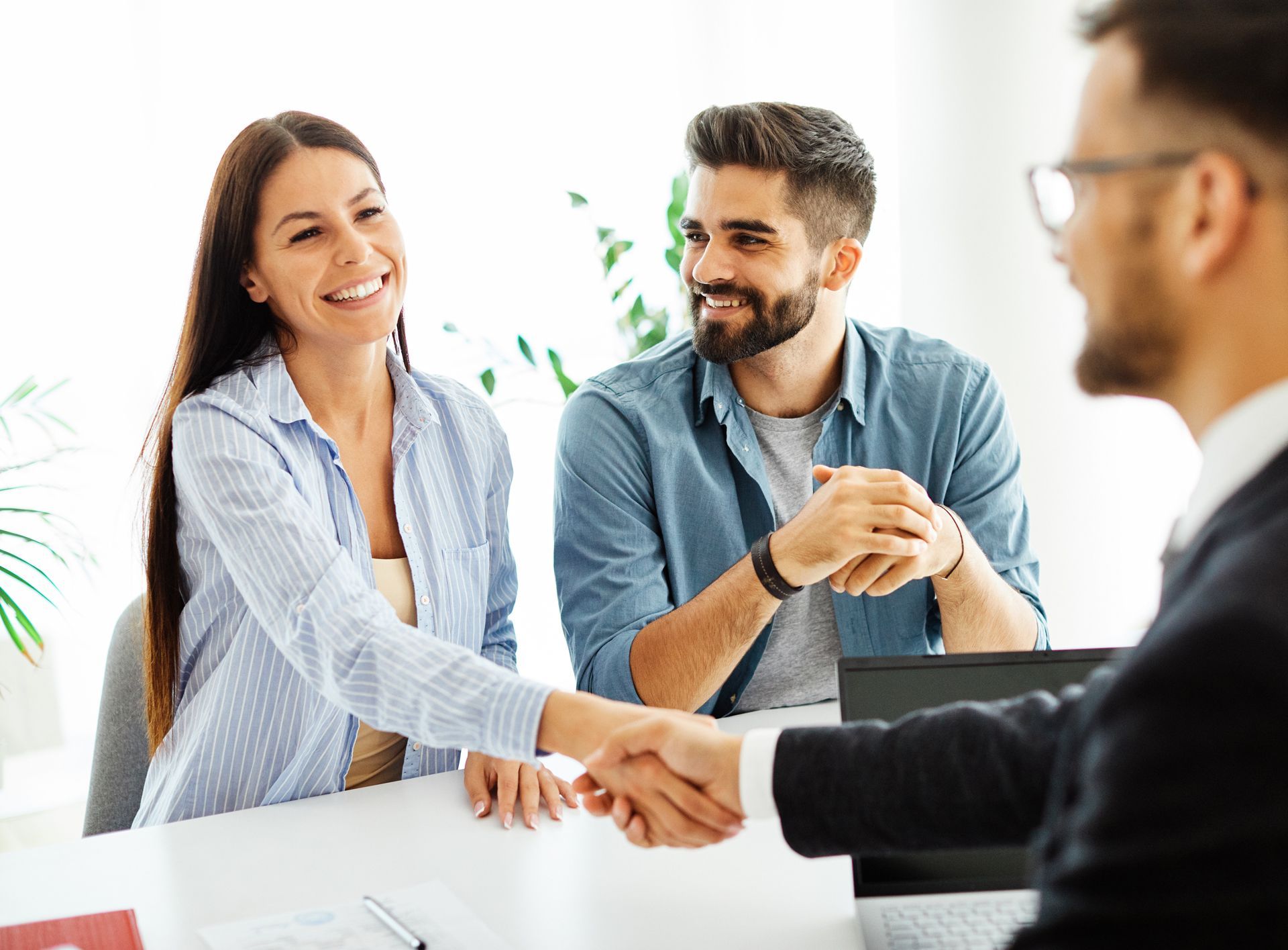 A Man and a Woman Are Shaking Hands With a Man in a Suit