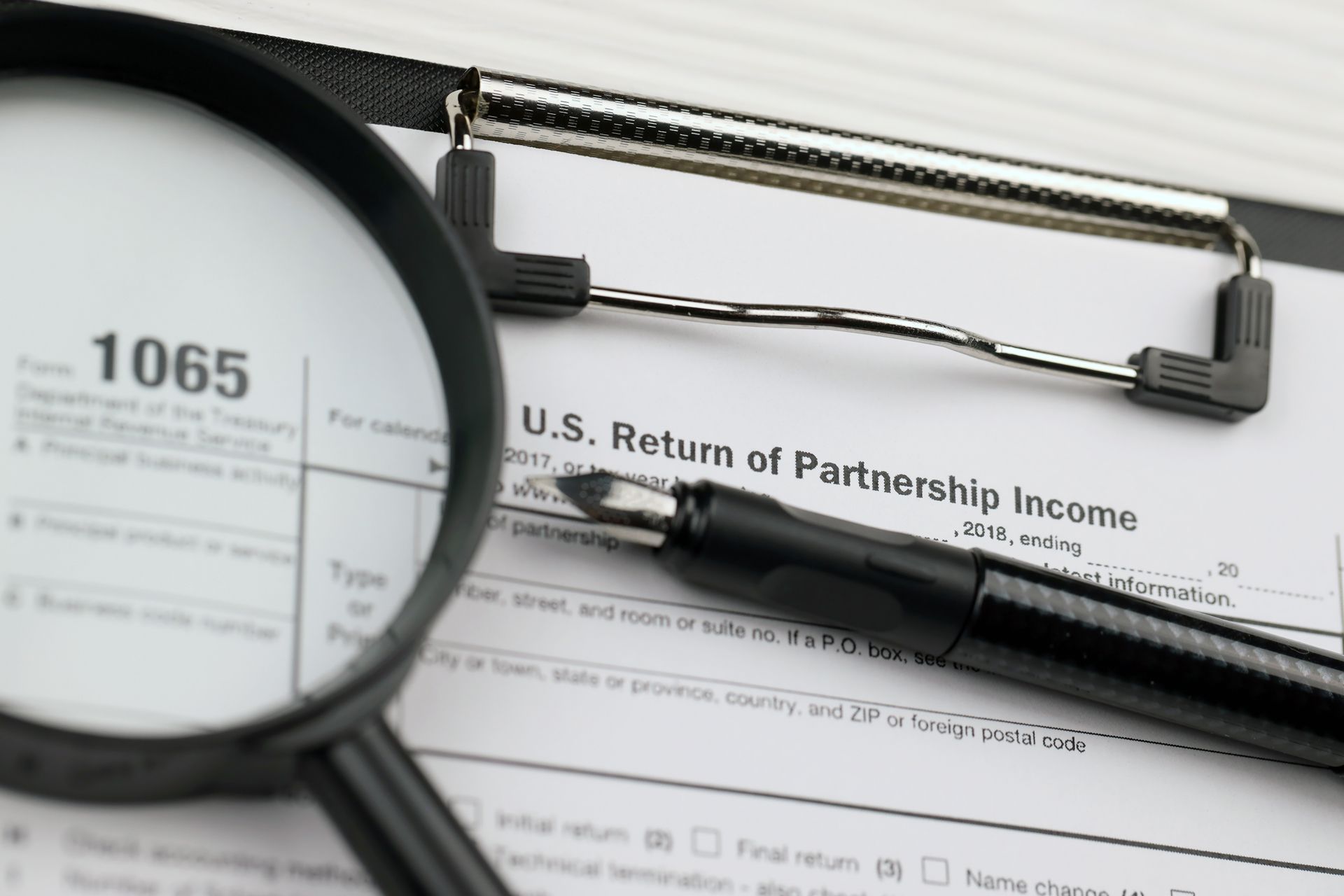 A Magnifying Glass is Sitting on Top of a Us Return of Partnership Income Form