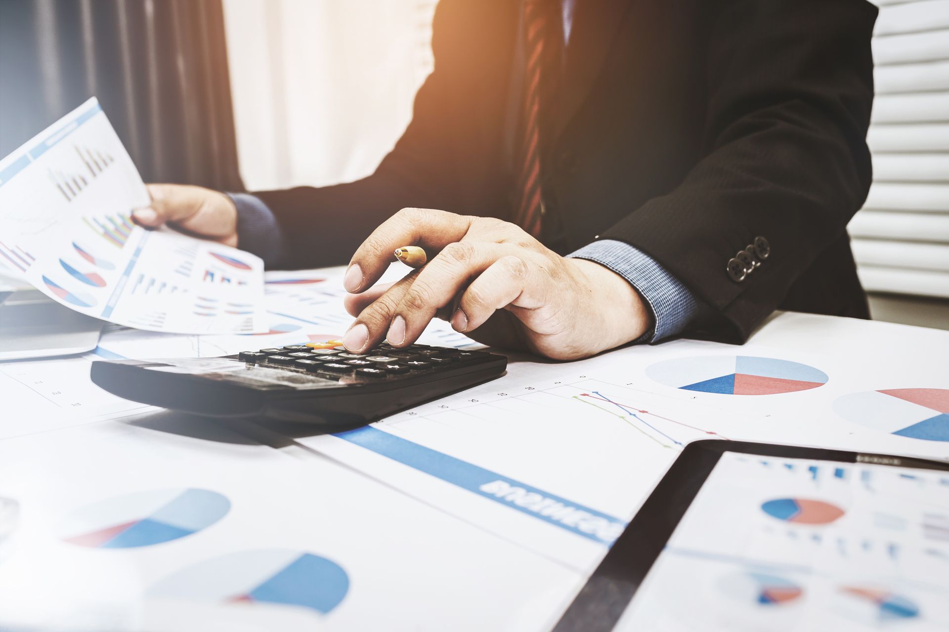 A Business Advisor is Sitting at a Desk Using a Calculator and a Pen