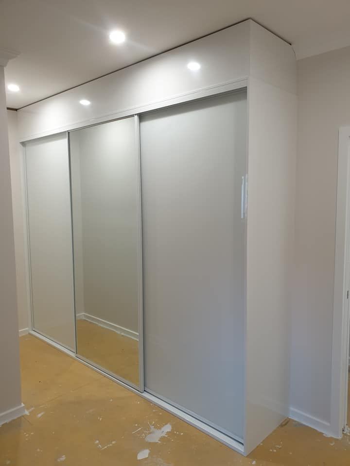 A White Wardrobe With Sliding Doors and Mirrors in a Hallway — Pacific Cabinets In Yamba, NSW