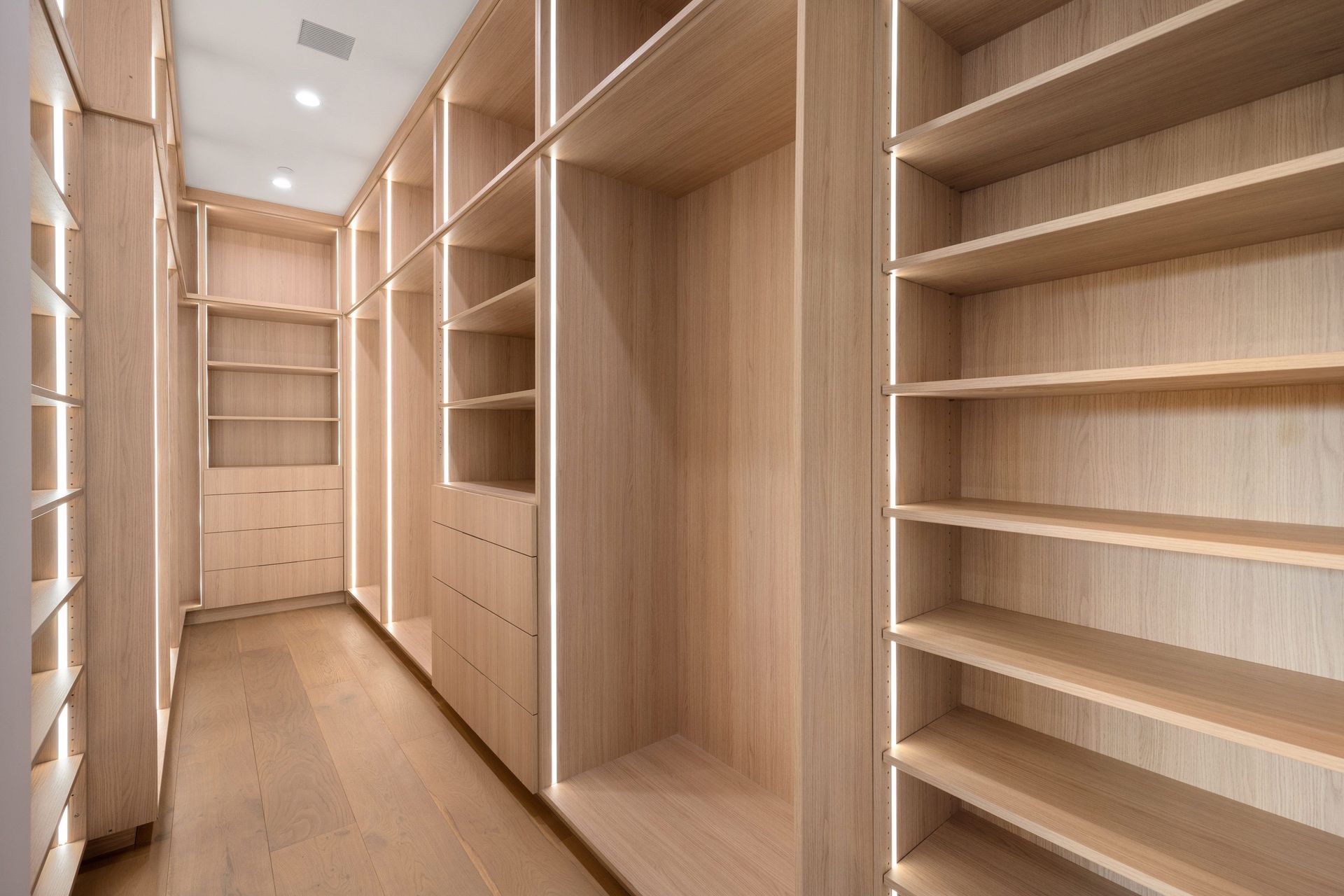 An Empty Walk in Closet With Wooden Shelves and Drawers — Pacific Cabinets In Yamba, NSW