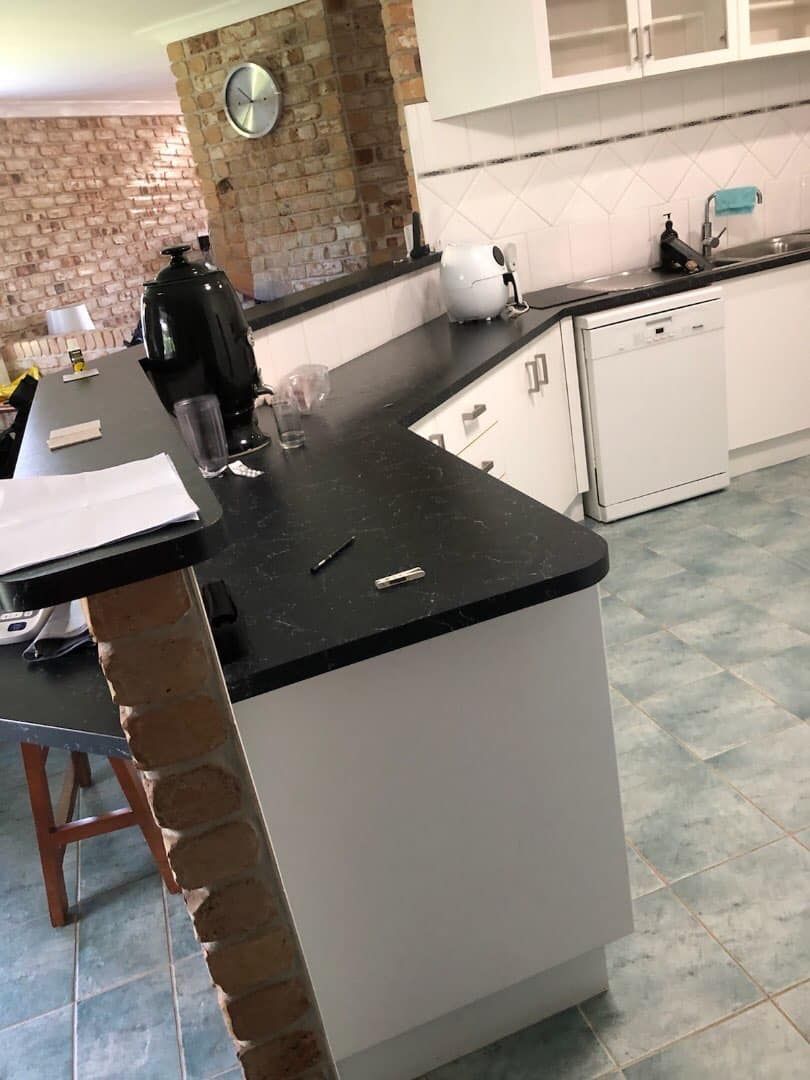 A Kitchen With a Black Counter Top and White Cabinets — Pacific Cabinets In Yamba, NSW