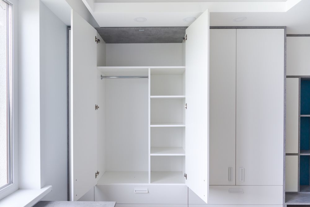 A White Wardrobe With the Door Open in a Room With a Window — Pacific Cabinets In Iluka, NSW