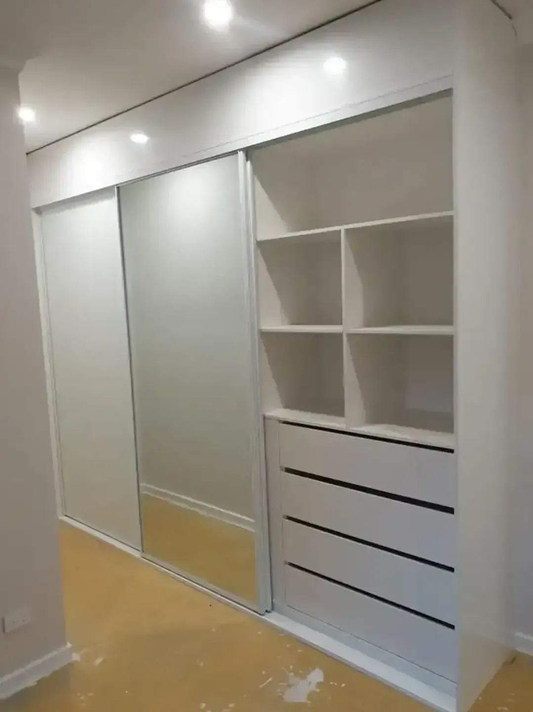 A Large White Wardrobe With Sliding Doors and Drawers in a Room — Pacific Cabinets In Yamba, NSW