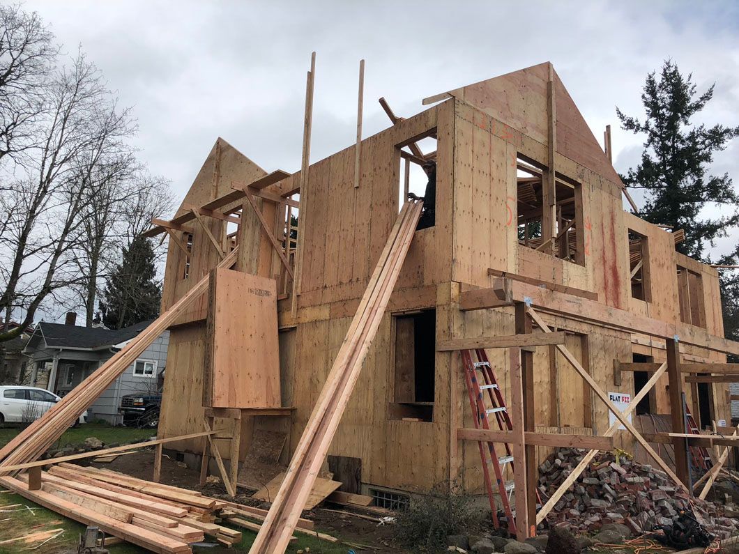 A house is being built with wooden beams and a ladder.