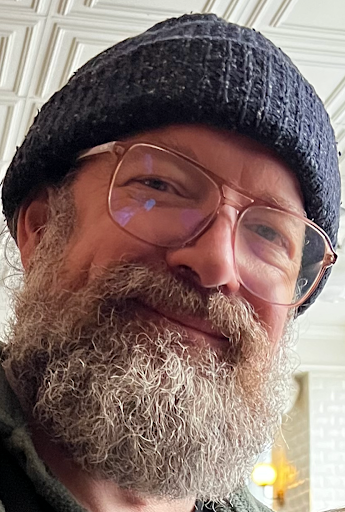 A man with a beard wearing glasses and a hat.