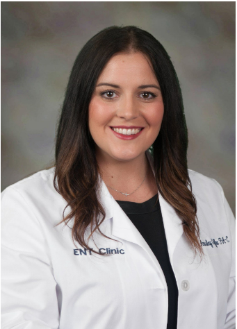 A woman in a white lab coat is smiling for the camera.