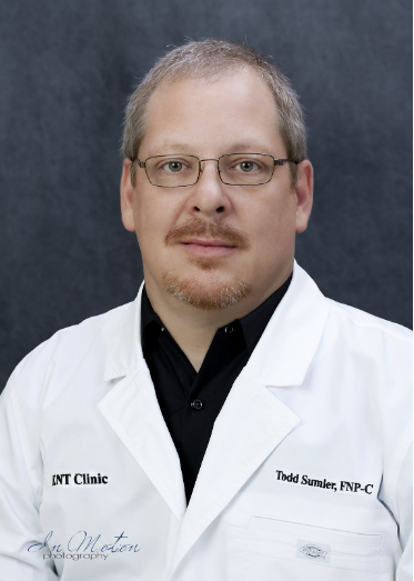 A man in a white lab coat with the name int clinic on it