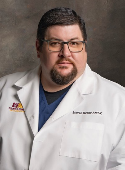 A man with glasses and a beard is wearing a white lab coat