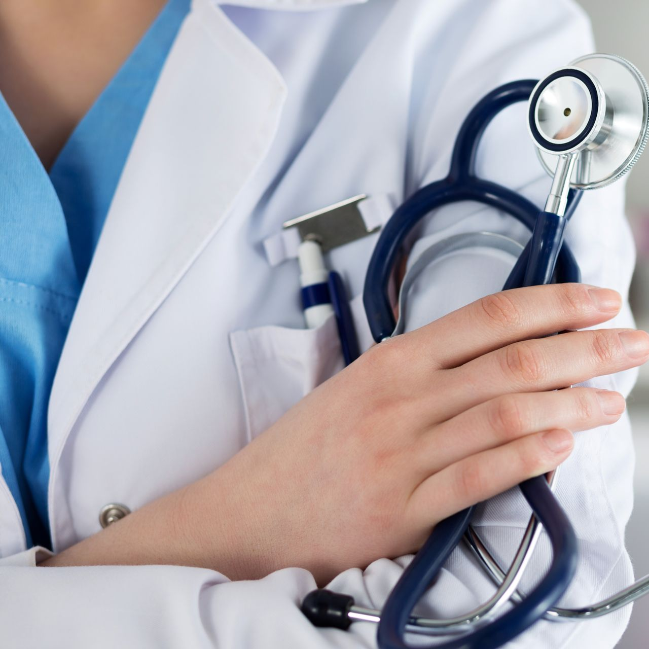 Man in dark suit smiles, with a medical setting blurred in background.