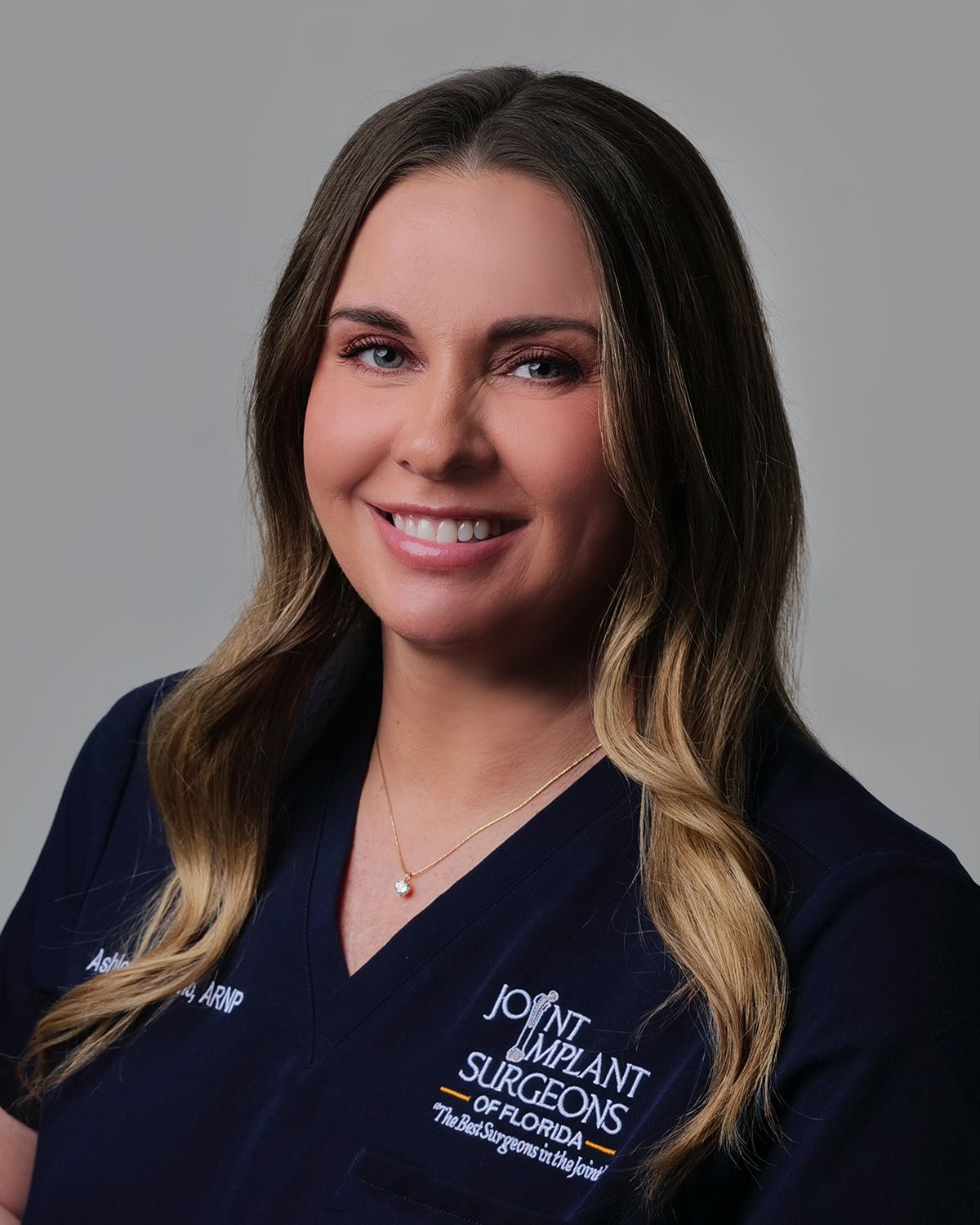 Woman with long, wavy blonde hair, blue eyes, smiling slightly, indoors.