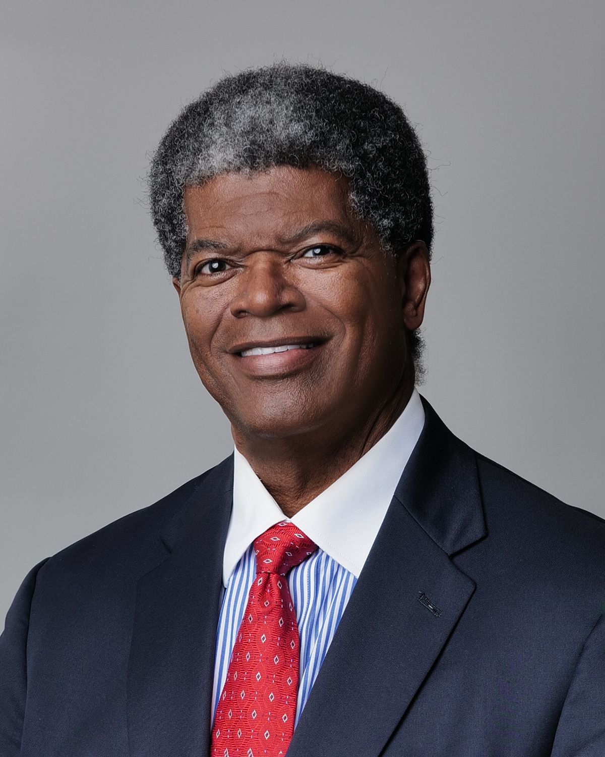 Man with glasses and a red tie smiling.