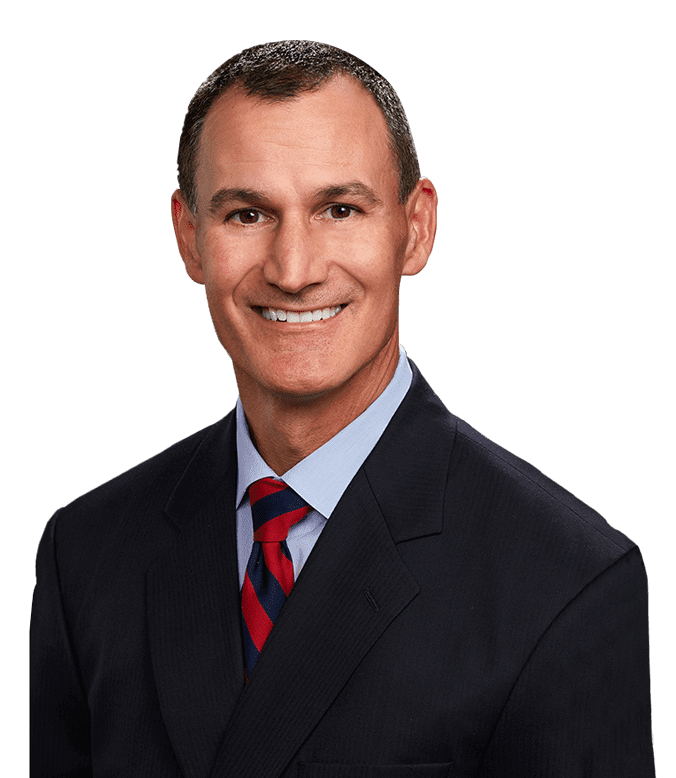 Man in suit smiling at the camera, with blue shirt and red-striped tie.