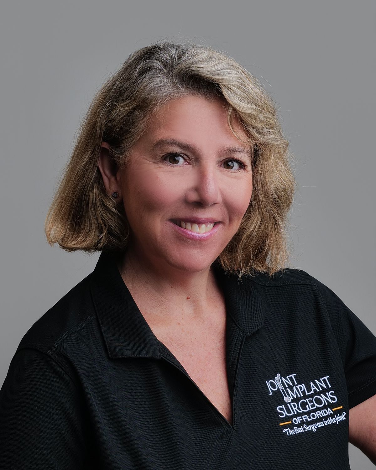 Man in suit smiling; blurred operating room background.