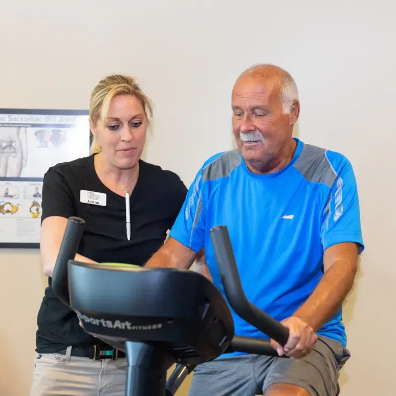 Man in a suit smiles at the camera; background blurred.