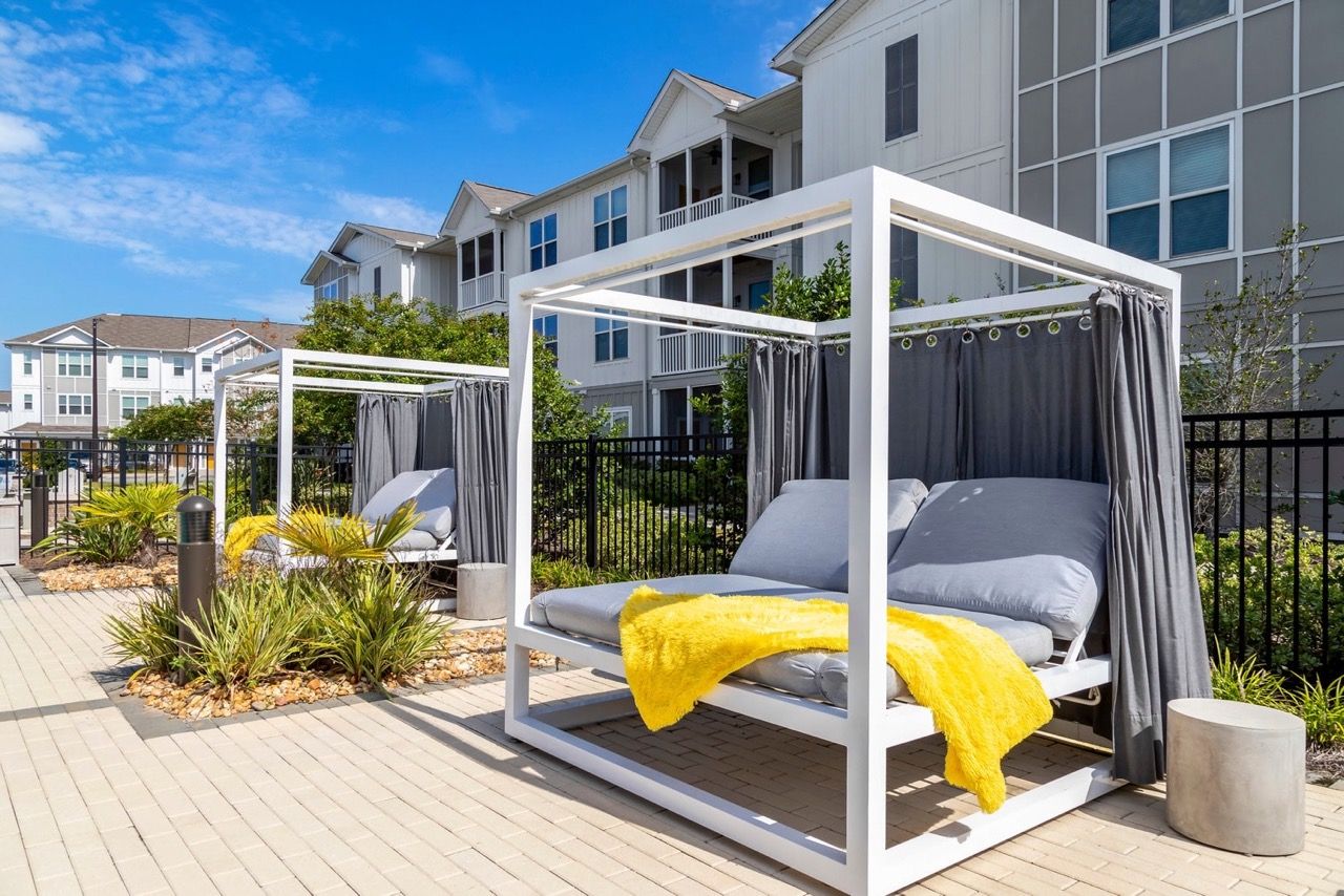 Outdoor communal lounge cabanas with curtains at an apartment complex.
