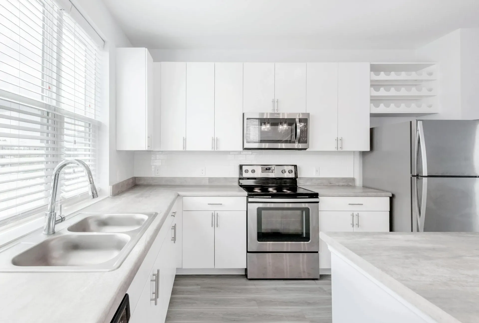 Bright white kitchen with stainless steel appliances, double sink, and white cabinetry.