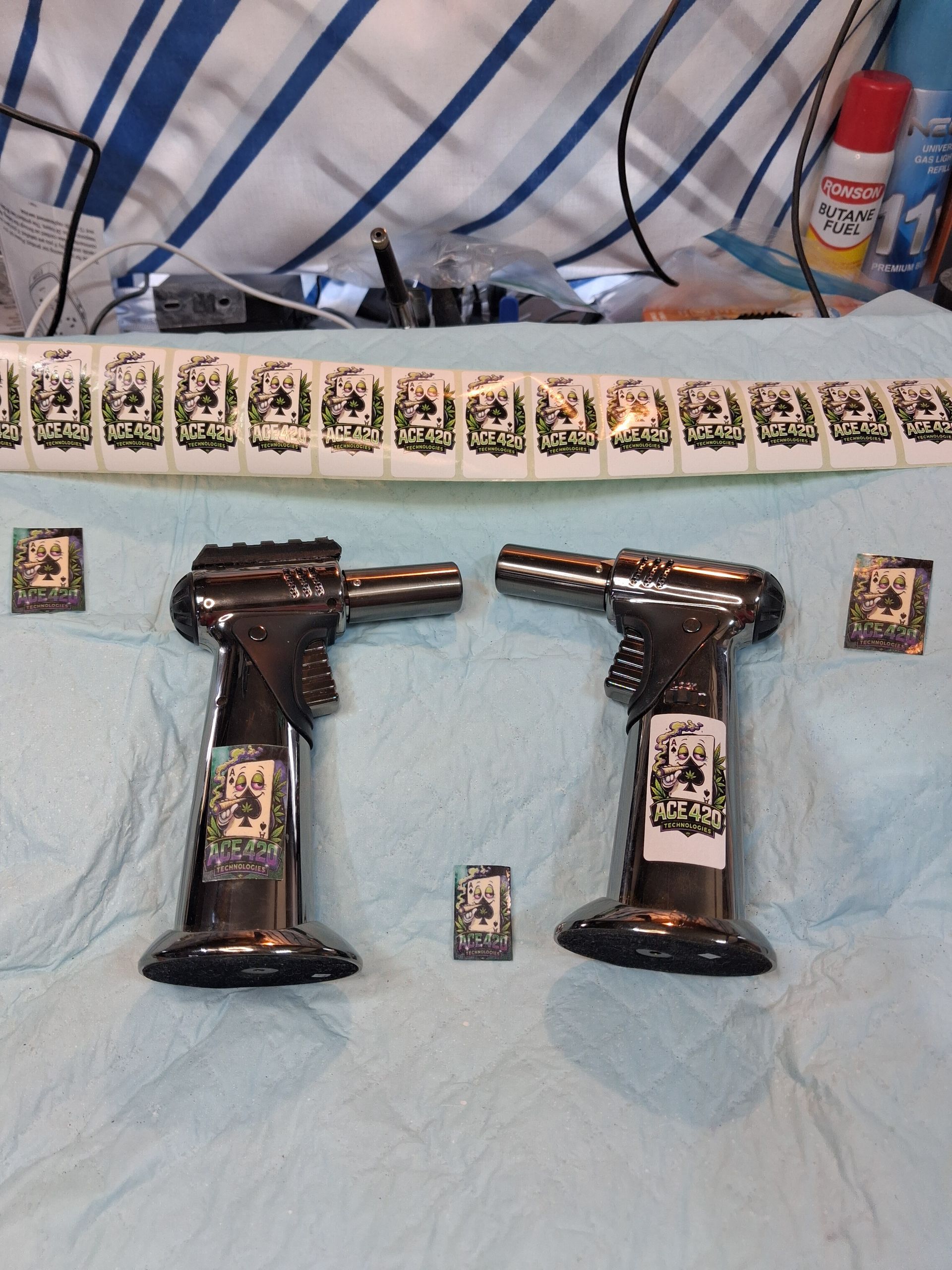 Two black handguns and spread-out cards on a light blue cloth, with more cards and a spray can in the background