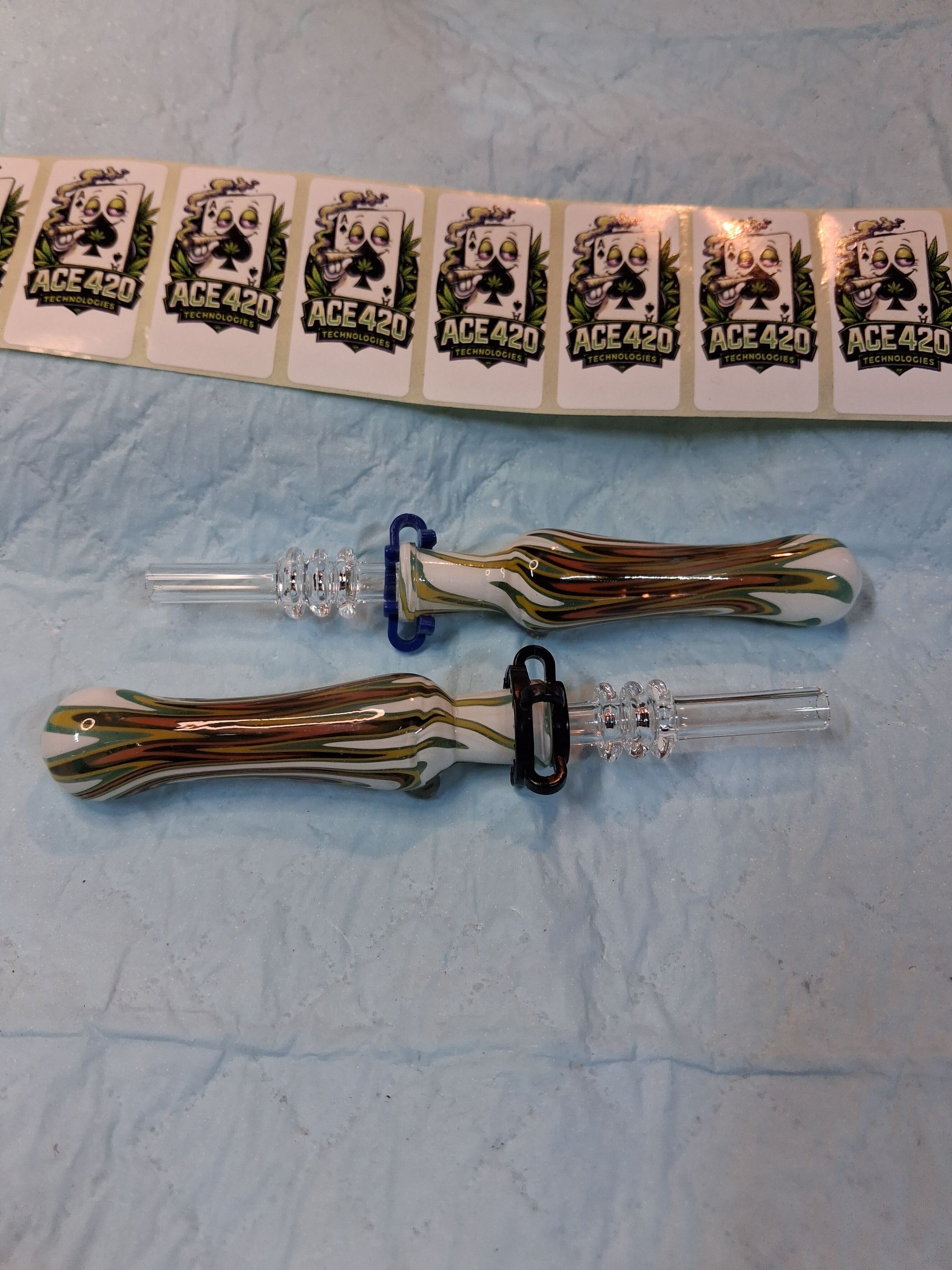 Two decorative clear glass wands with gold ribbon tails on a blue cloth, with patterned cards above