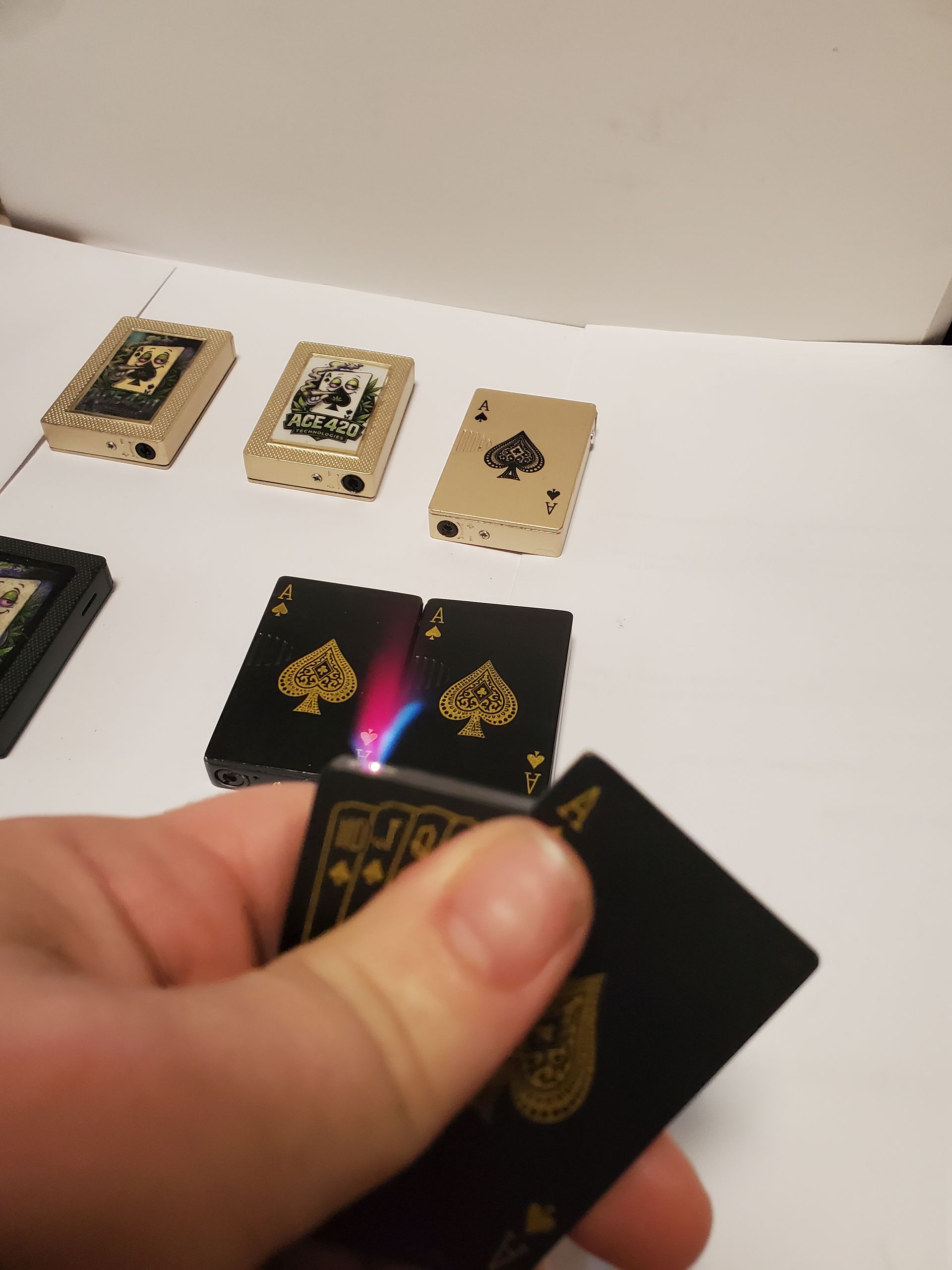Hand holding black and gold playing cards over a table with several cards laid out and one card glowing with colorful light.