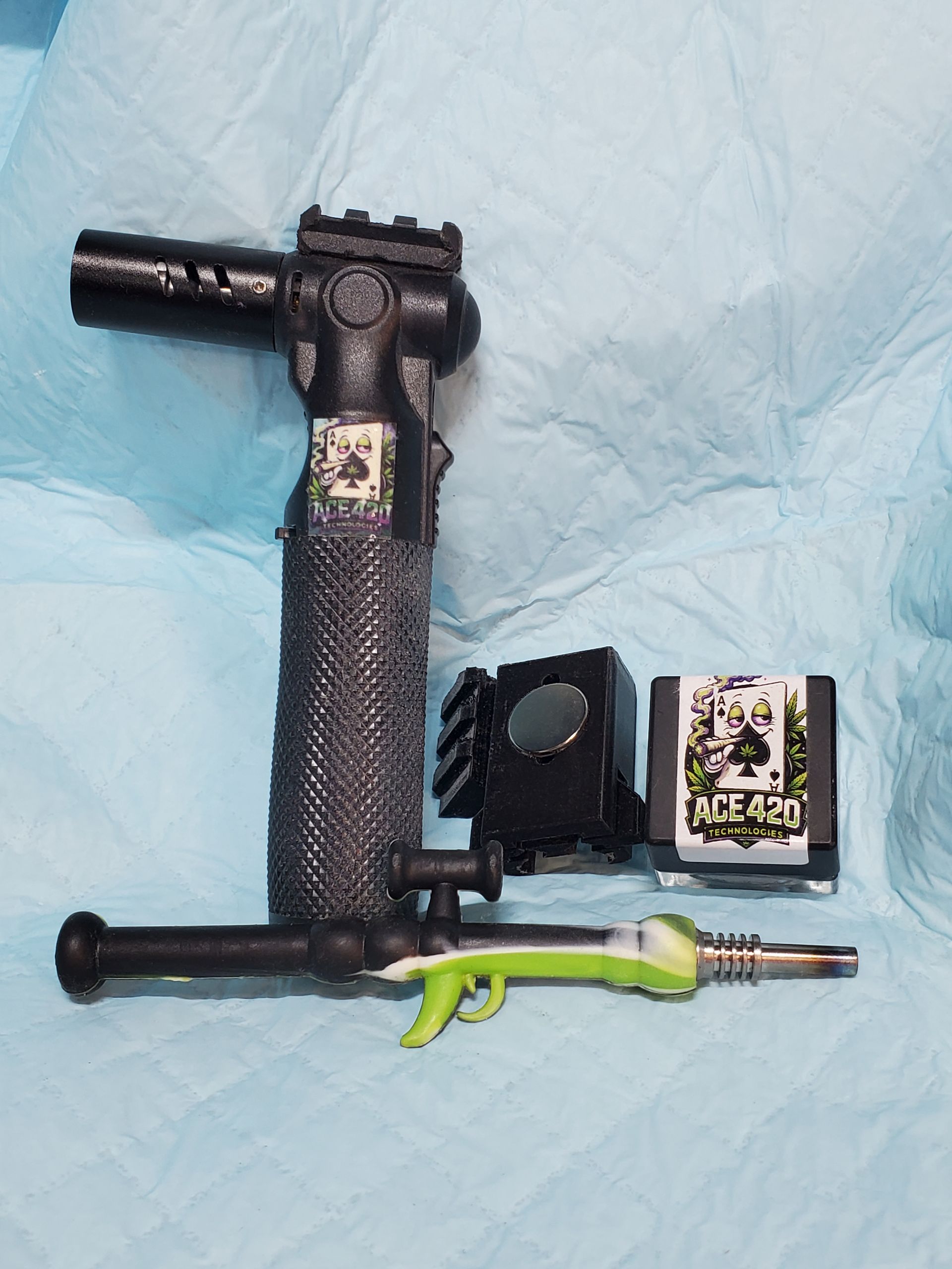 Black T-shaped tool with textured handle, lime-green attachment, and two small accessory parts on a blue cloth.