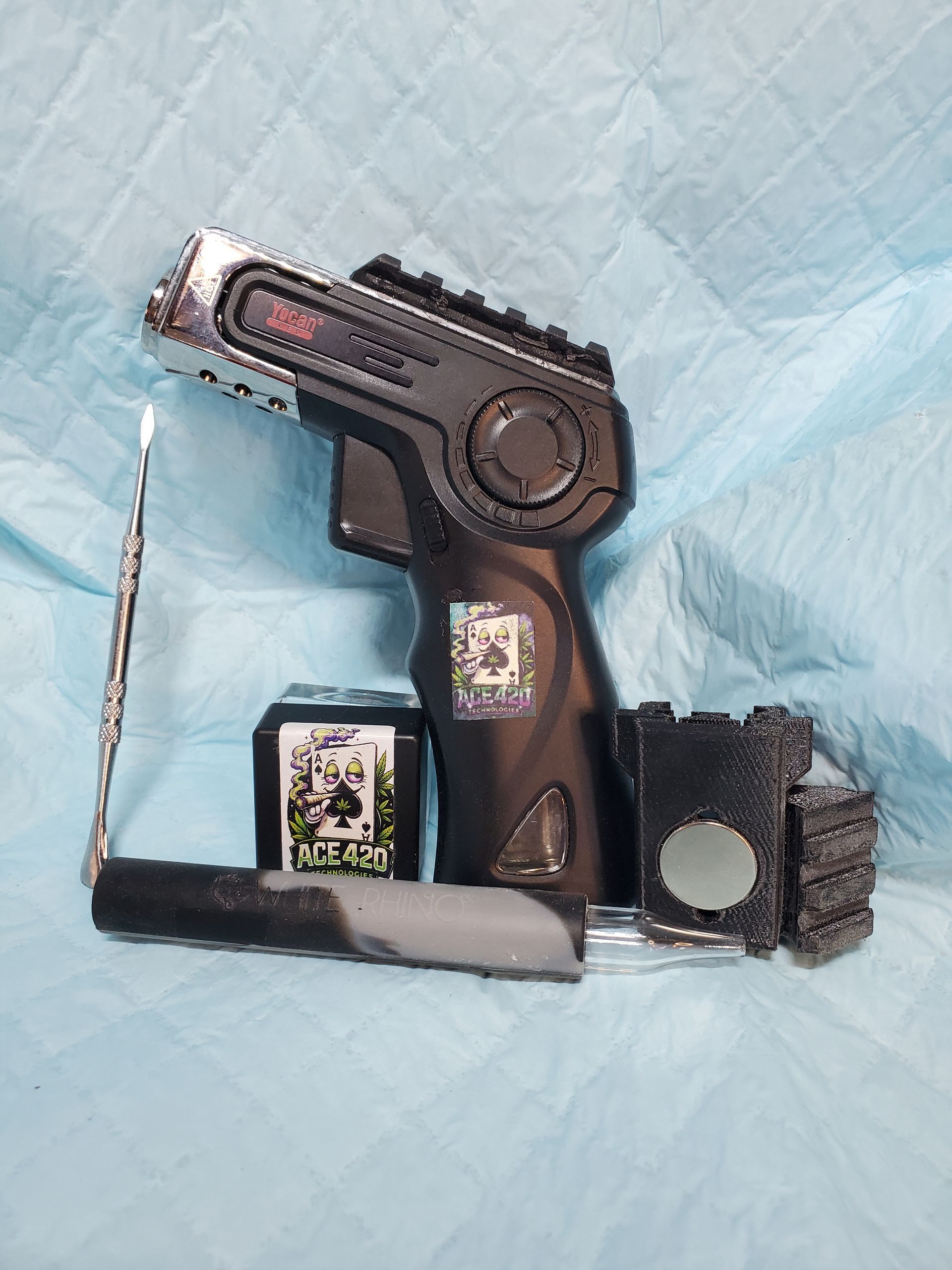 Toy black gun made from a building block set, with a gray grip and attached chain on a blue quilted surface